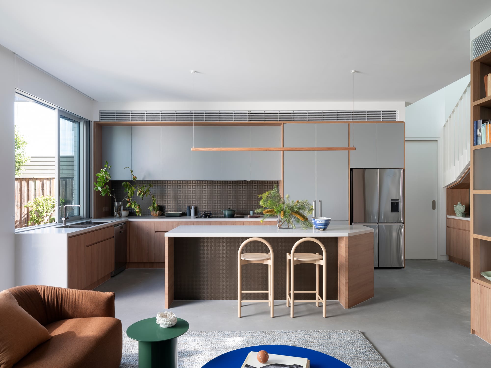 Merrilands by BIJL Architecture. Photography by Tom Ferguson. Open plan kitchen and living space with brown splashback, white and timber joinery and concrete floors. 