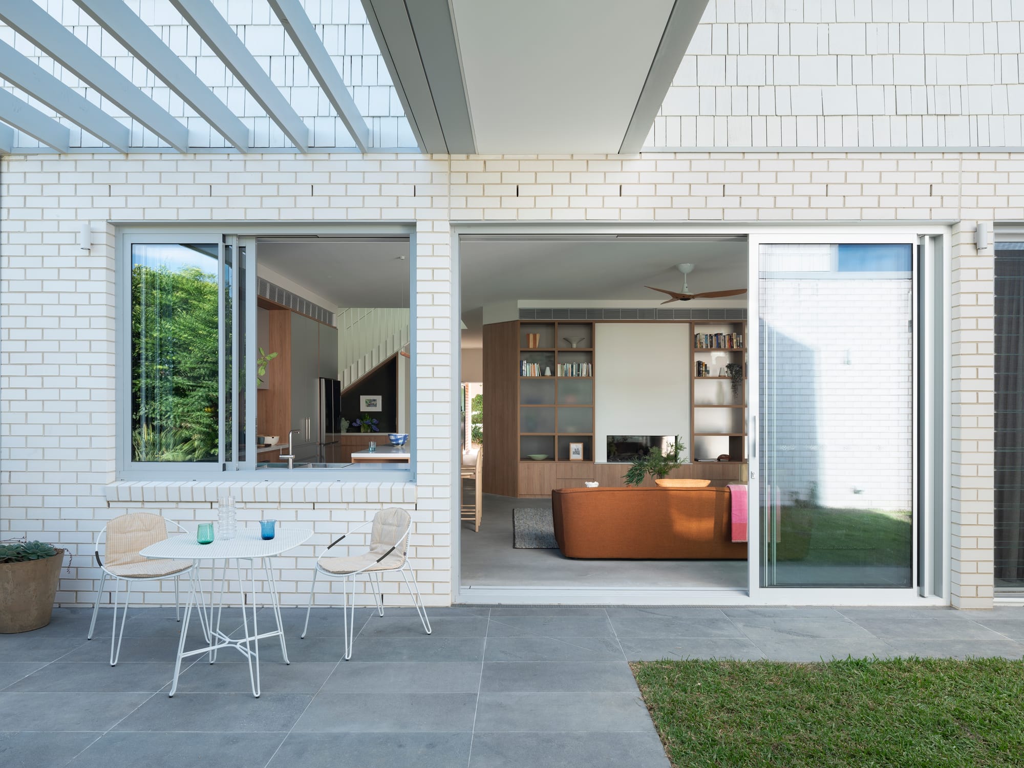 Merrilands by BIJL Architecture. Photography by Tom Ferguson. Outdoor patio on ground floor of residential home with concrete pavers, white brick facade and exposed pergola. 