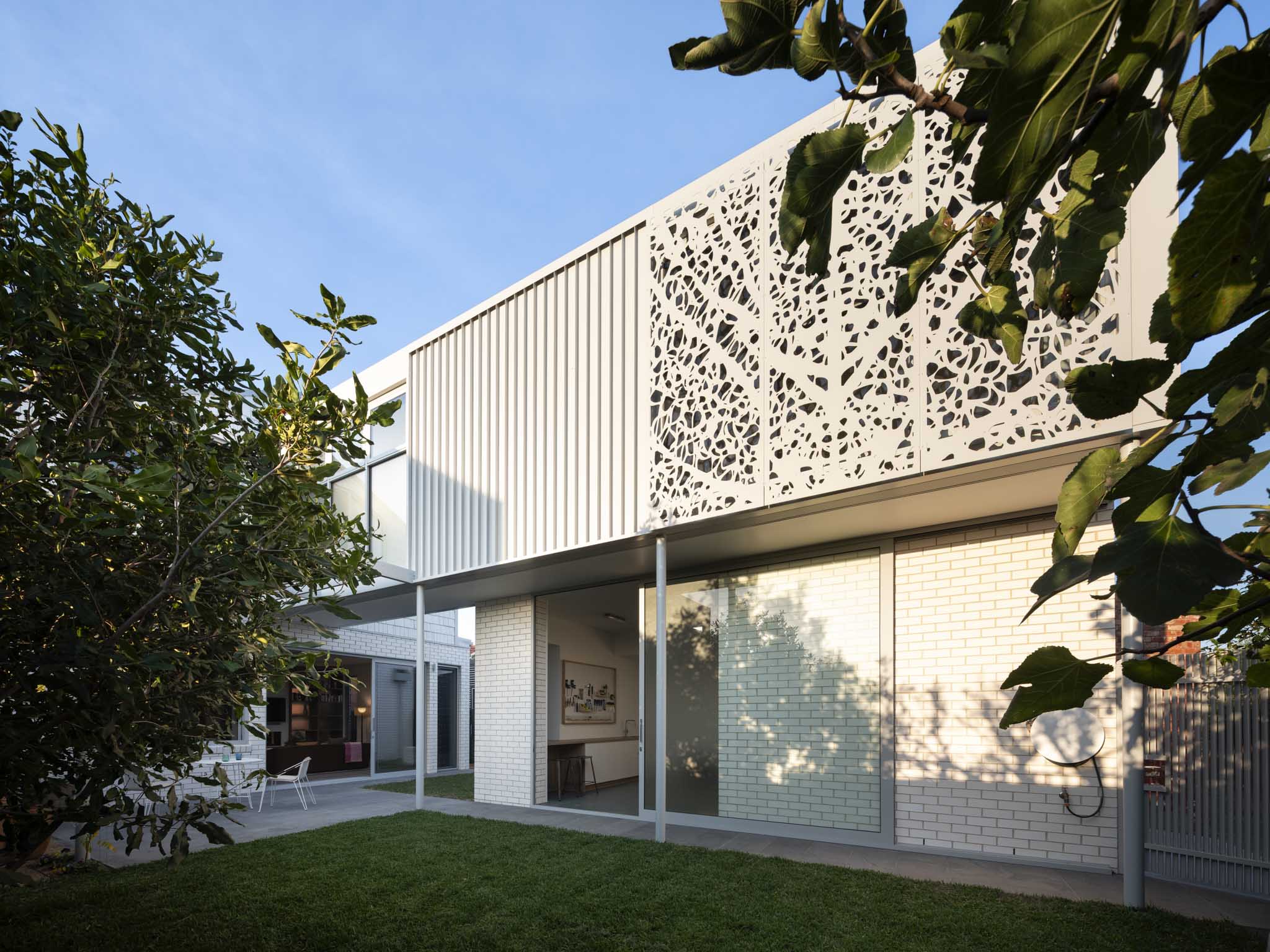 Merrilands by BIJL Architecture. Photography by Tom Ferguson. Metal clad roofline peaking above wooden slat fence with vines growing on top. 