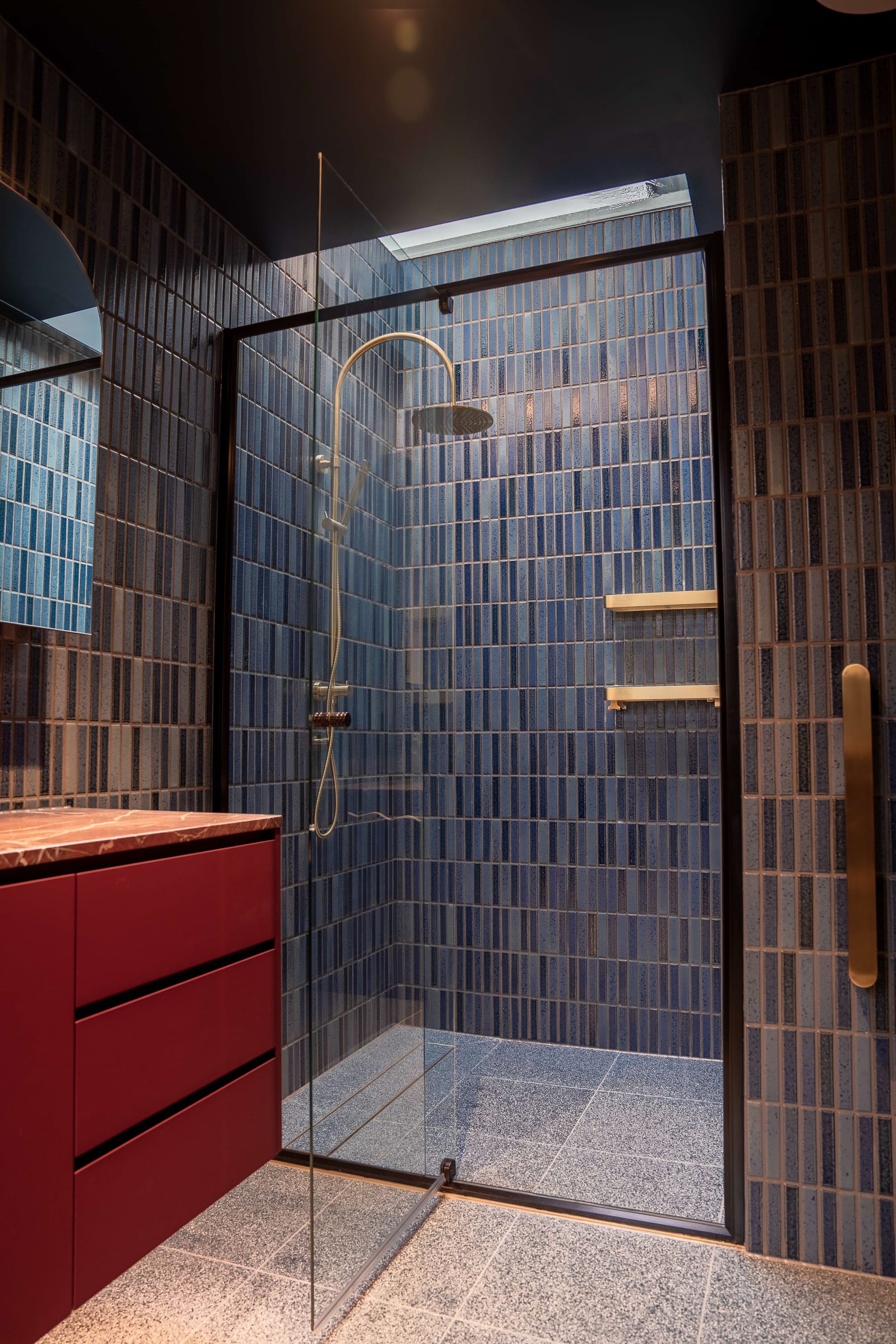 Murrumbeena by PREM.BUILT. Image copyright of Prem.Built. Bathroom with mosaic wall tiles, in shower with glass screen and as a splashback behind burgundy vanity. 
