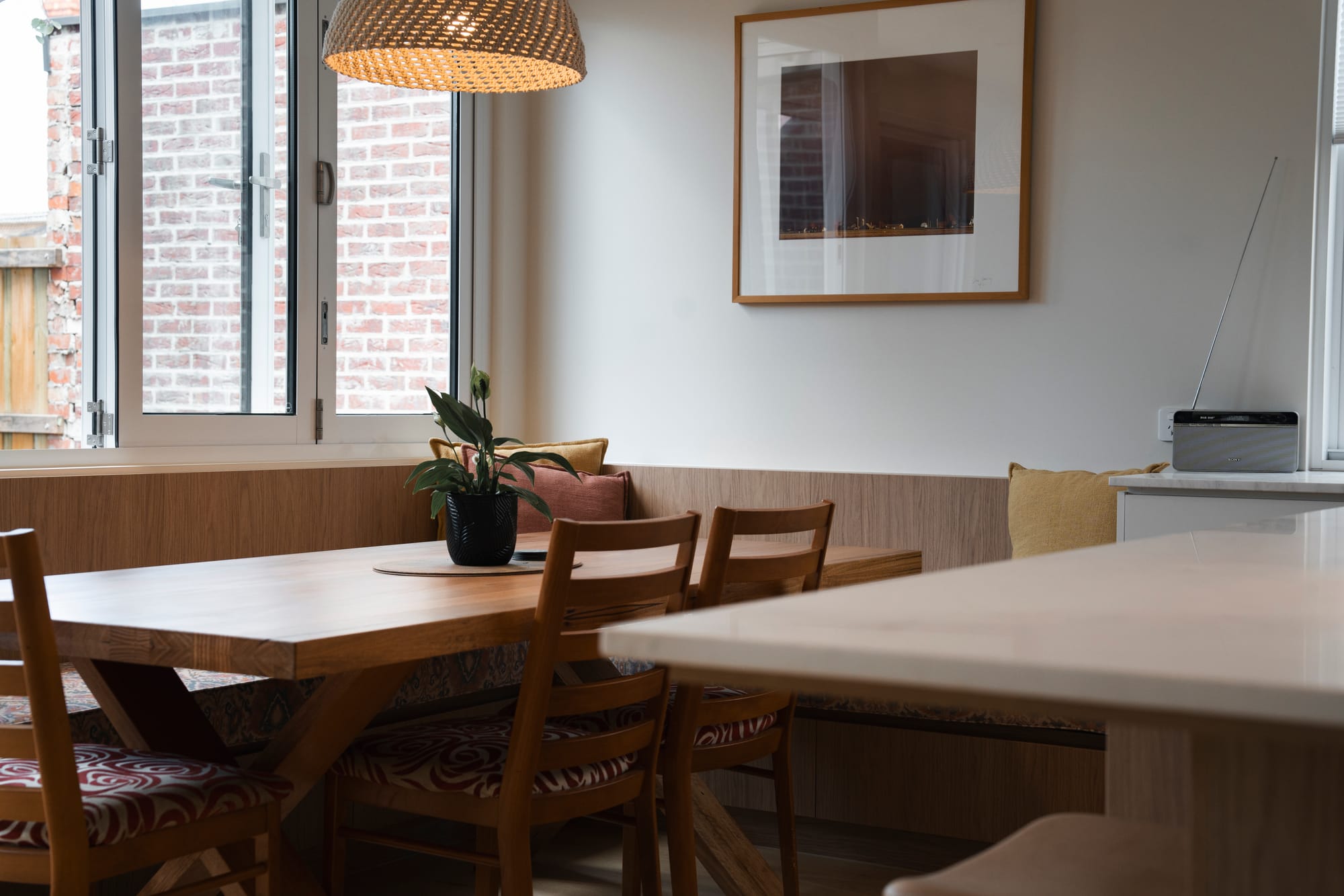 Port Melbourne 2.0 by PREM.BUILT. Image copyright of Prem.Built. Dining nook with timber bench seating, table and chairs with rattan pendant light and white window. 