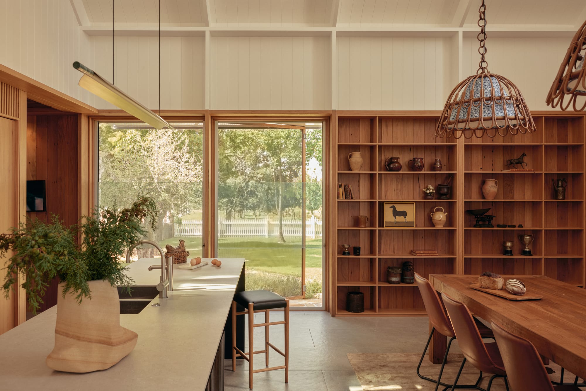 Binnum Homestead by Alexandra Buchanan Architecture. Photography by Cieran Murphy. Open plan kitchen and dining room with full height timber bookshelves running the length of the wall. 