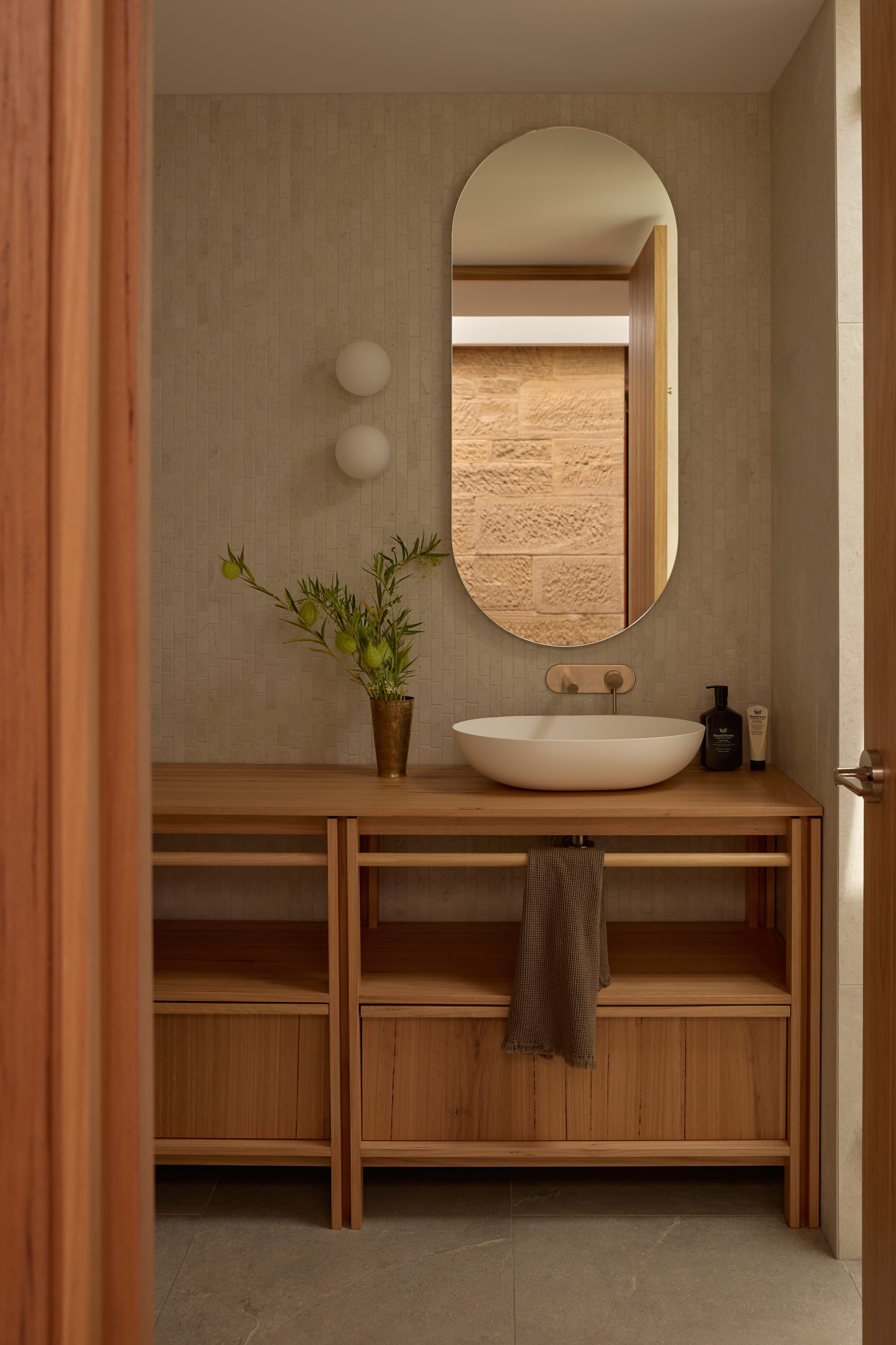 Binnum Homestead by Alexandra Buchanan Architecture. Photography by Cieran Murphy. Bathroom with timber cabinet, raised basin, oval mirror and sandstone walls. 