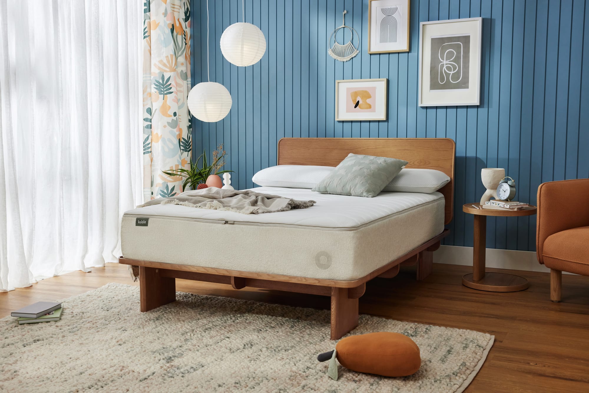 Kirribilli Bed Frame by Koala. Timber bedframe with exposed mattress in room with blue clad walls, timber floors and white rug.