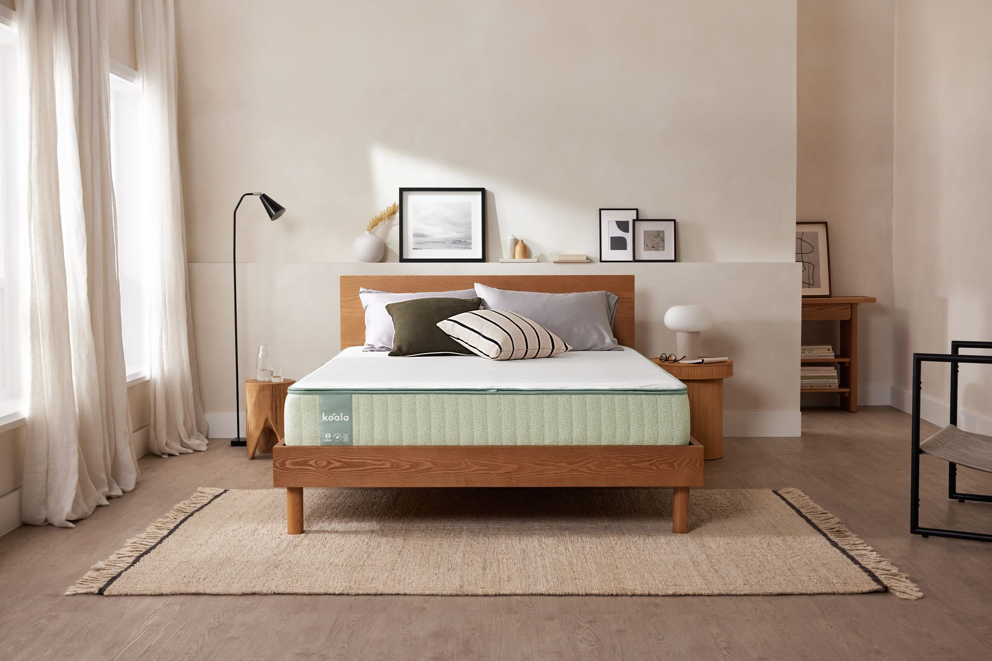 The Koala Mattress by Koala. Timber bedframe with white and light green exposed mattress, in room with white walls and timber floors. 