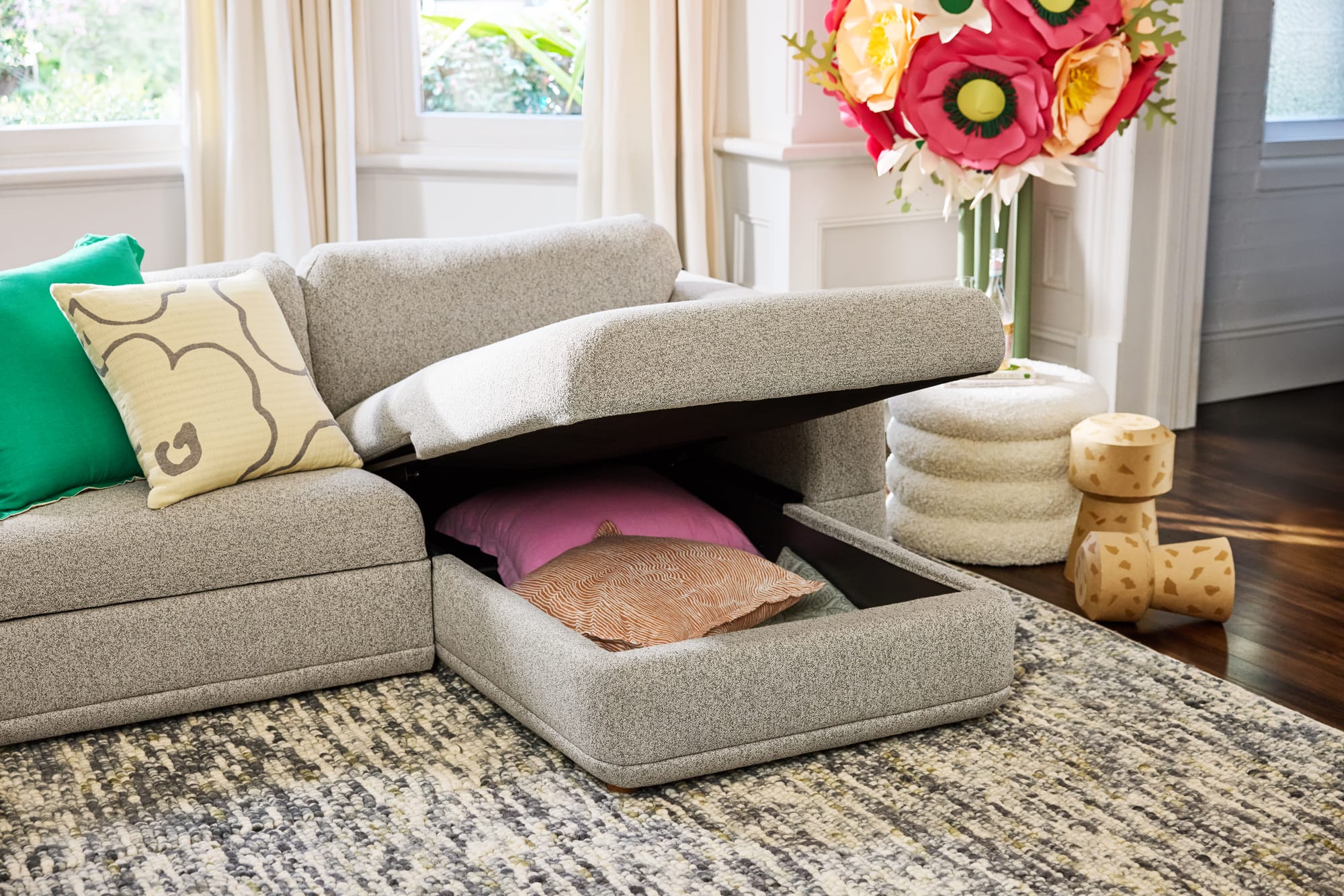 Wanda Sofa Bed in Paperbark by Koala. Grey modular lounge with chaise storage unit with pink and orange pillows inside. 