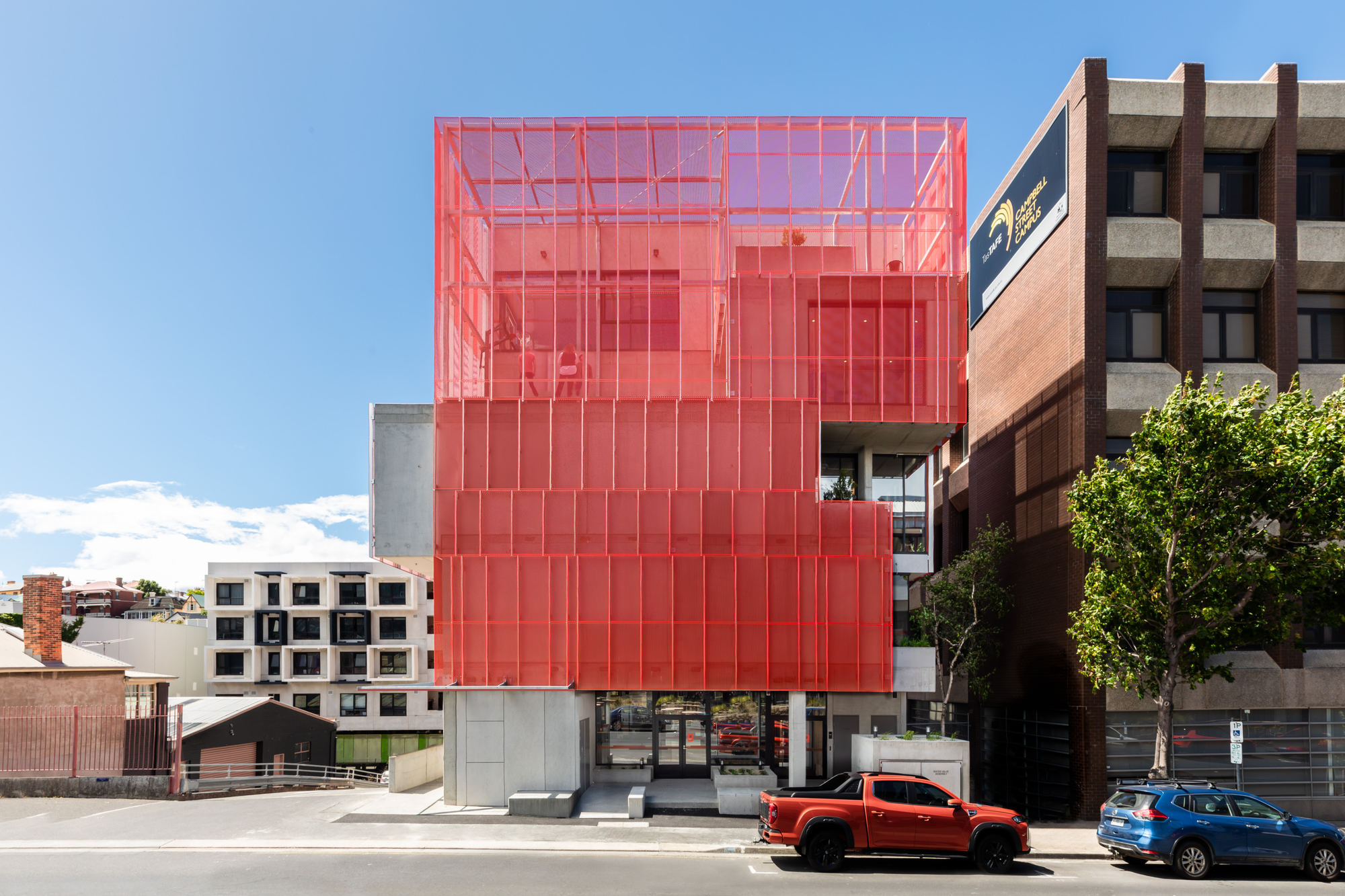 Youth 2 Independence (Y2I) by Liminal Studio. Photography by Natasha Mulhall Photography. Multistorey building with red metal, semi-sheer exterior and asymmetrical exterior. 