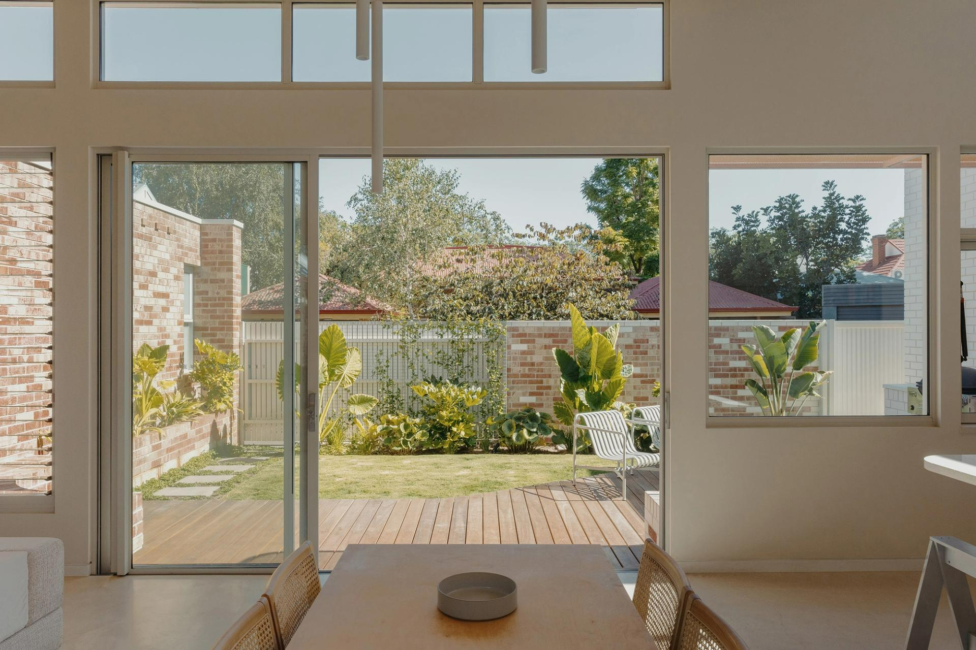 Laneway in HIFI by RADS. Open plan dining space with double height white walls overlooking deck and garden. 