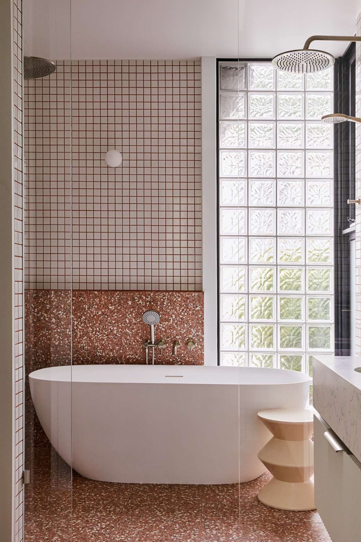 Park St by SGKS ARCH. Photography by Tania Lee. Bathroom with freestanding white bathtub, speckled terracotta floor tiles, glass bricks and white wall tiles with red grout. 