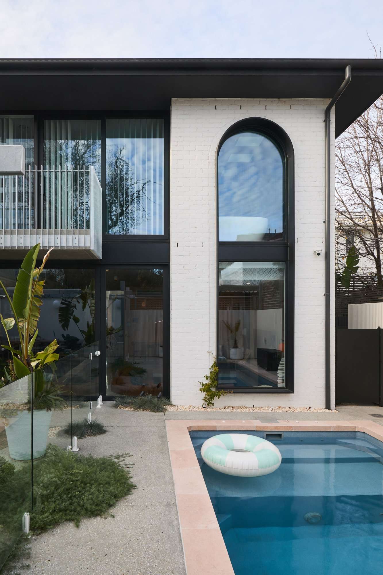 Park St by SGKS ARCH. Photography by Tania Lee. Rear facade of home with black window frames, white brick walls, and a pool. 