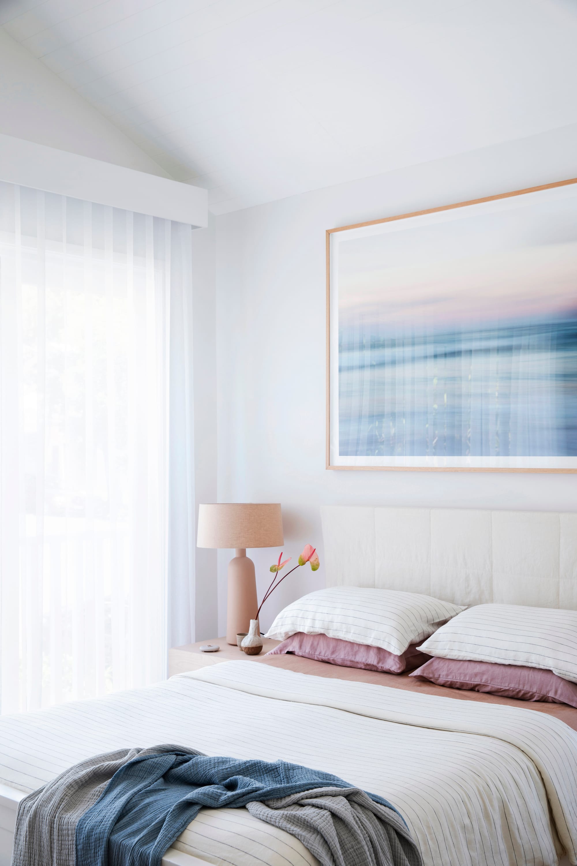 Bondi Beach House by Baikie Corr Architecture. Photography by Chris Warnes. Bedroom with light linen, pink pillows, pastel wall art, and a pink lamp.