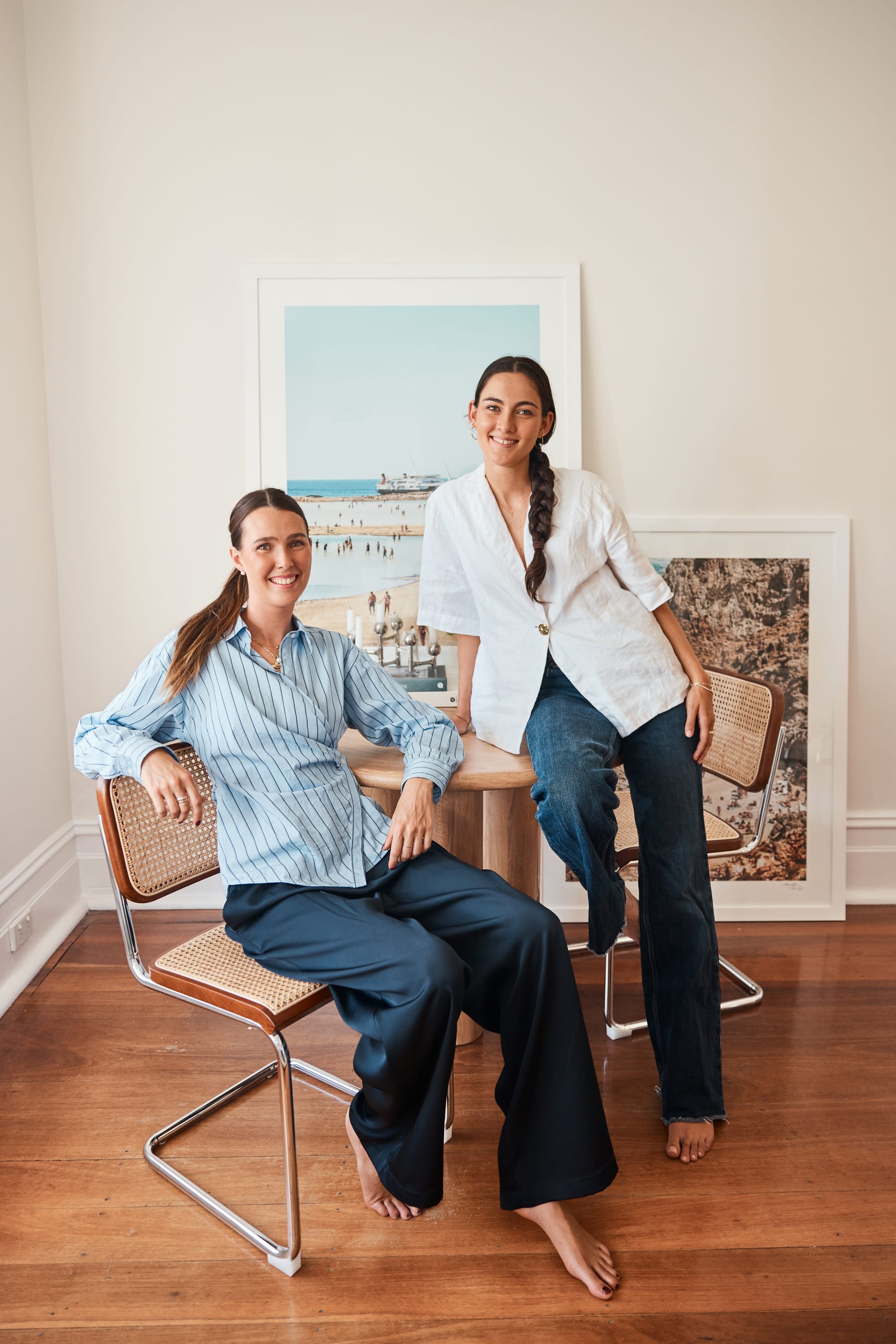 Ishbel and Bonnie Laing of Bel.Bon. Design. Photography by Sana Brotherson. Two young women in blue pants and dress shirts lounging and smiling. 