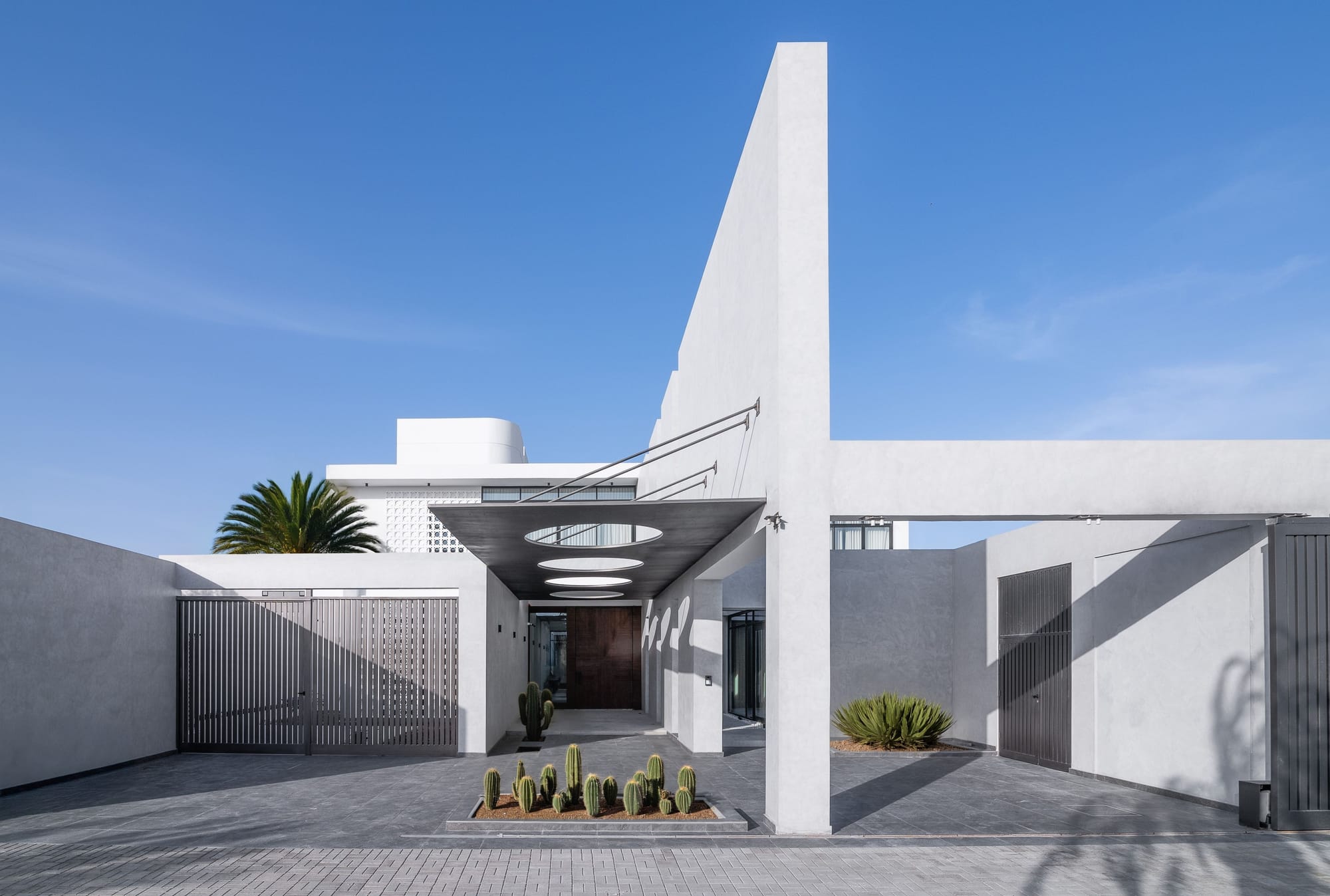 Veil House by ENCLAVE Architects. Photography by Hassan Arante & Gener Rayes. Exterior of contemporary home with white finish, cactus garden and long walkway. 