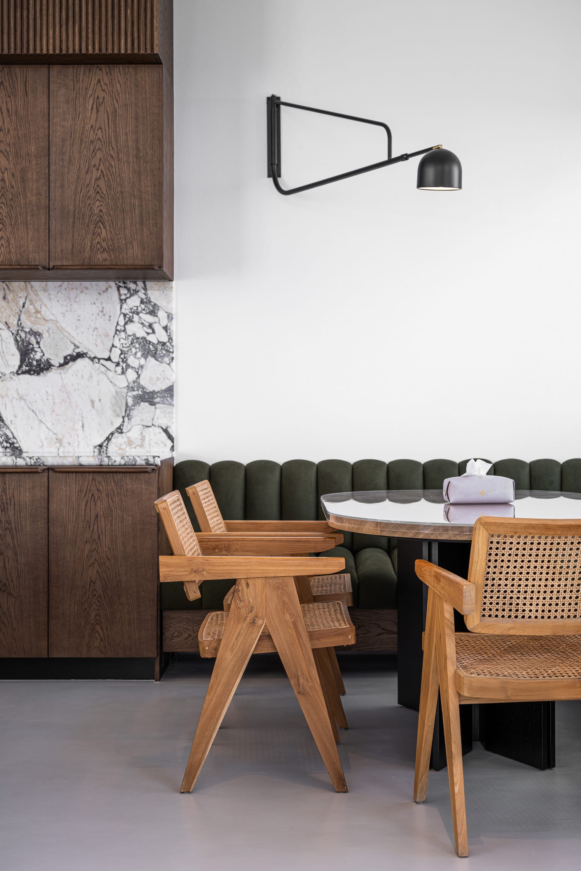 Veil House by ENCLAVE Architects. Photography by Hassan Arante & Gener Rayes. Dining room with tufted moss green bench seat, rattan timer dining chairs and black and glass dining table. 