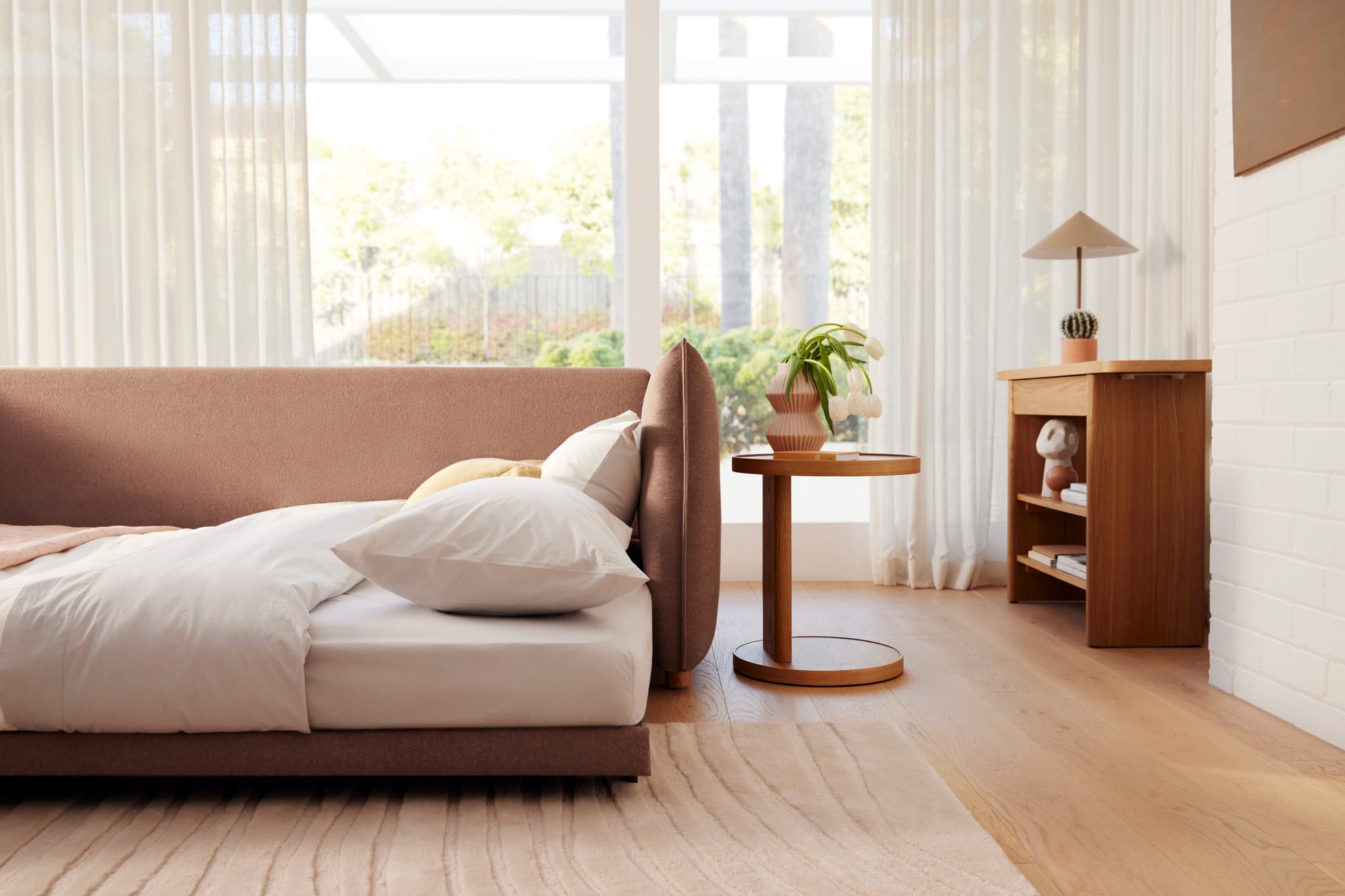 Koal Byron Bay Sofa Bed in Blush Sunset. Blush sofa bed folded out into bed with white linen, in room with timber floors and white walls. 