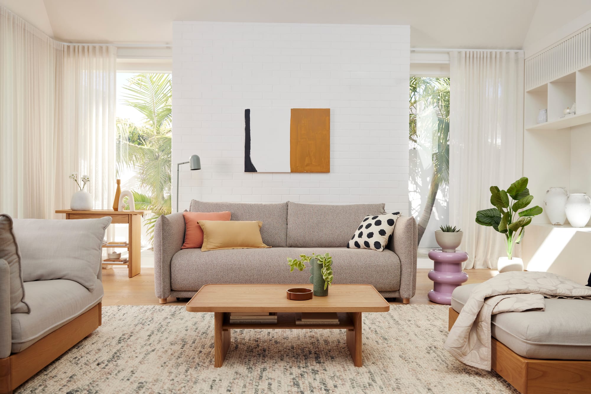 Kola Byron Sofa Bed in Cappucino. Living space with grey couches, timber flooring and coffee table and white brick walls. 