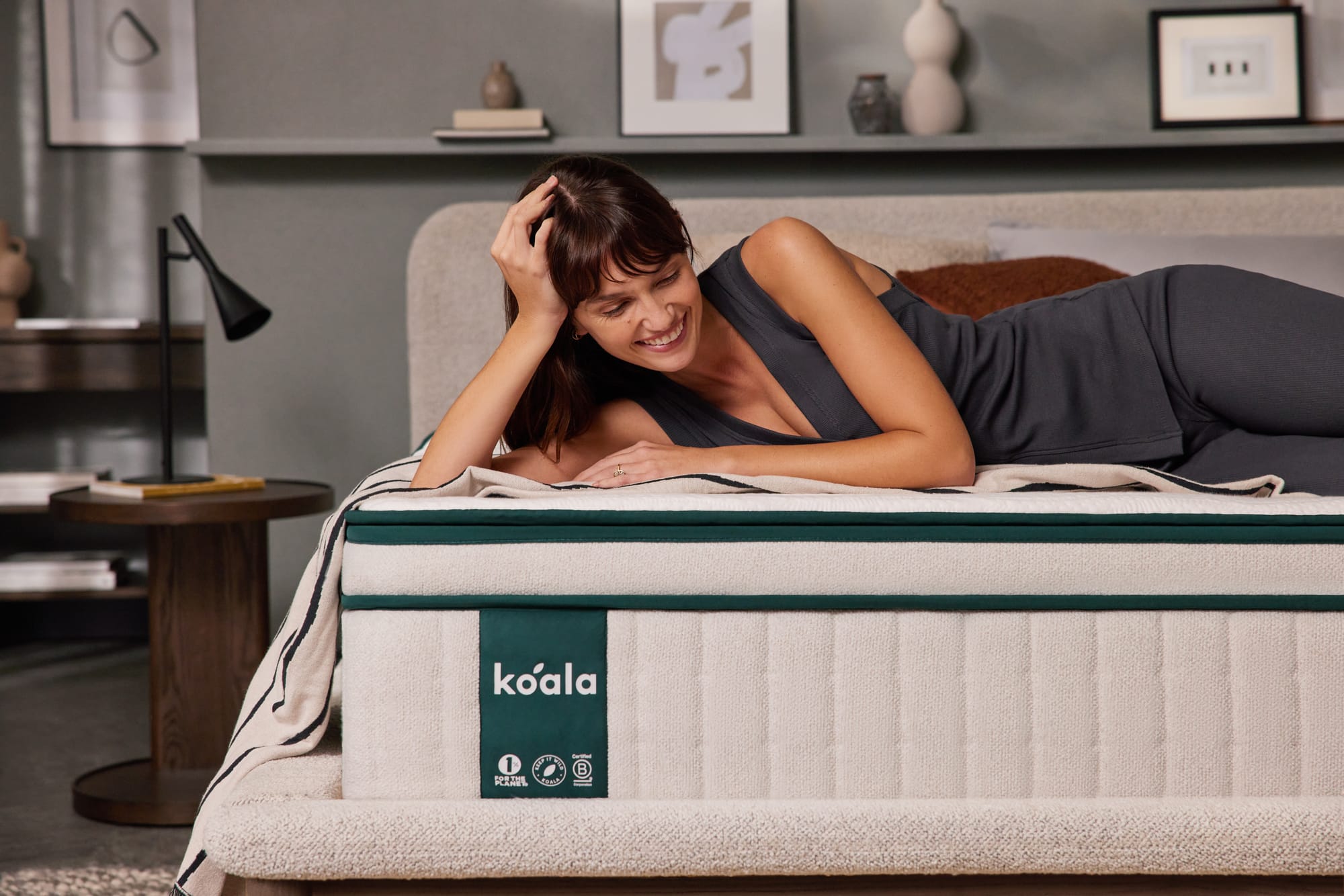 Koala Luxe Mattress. Woman in grey outfit smiling, lying on mattress. 