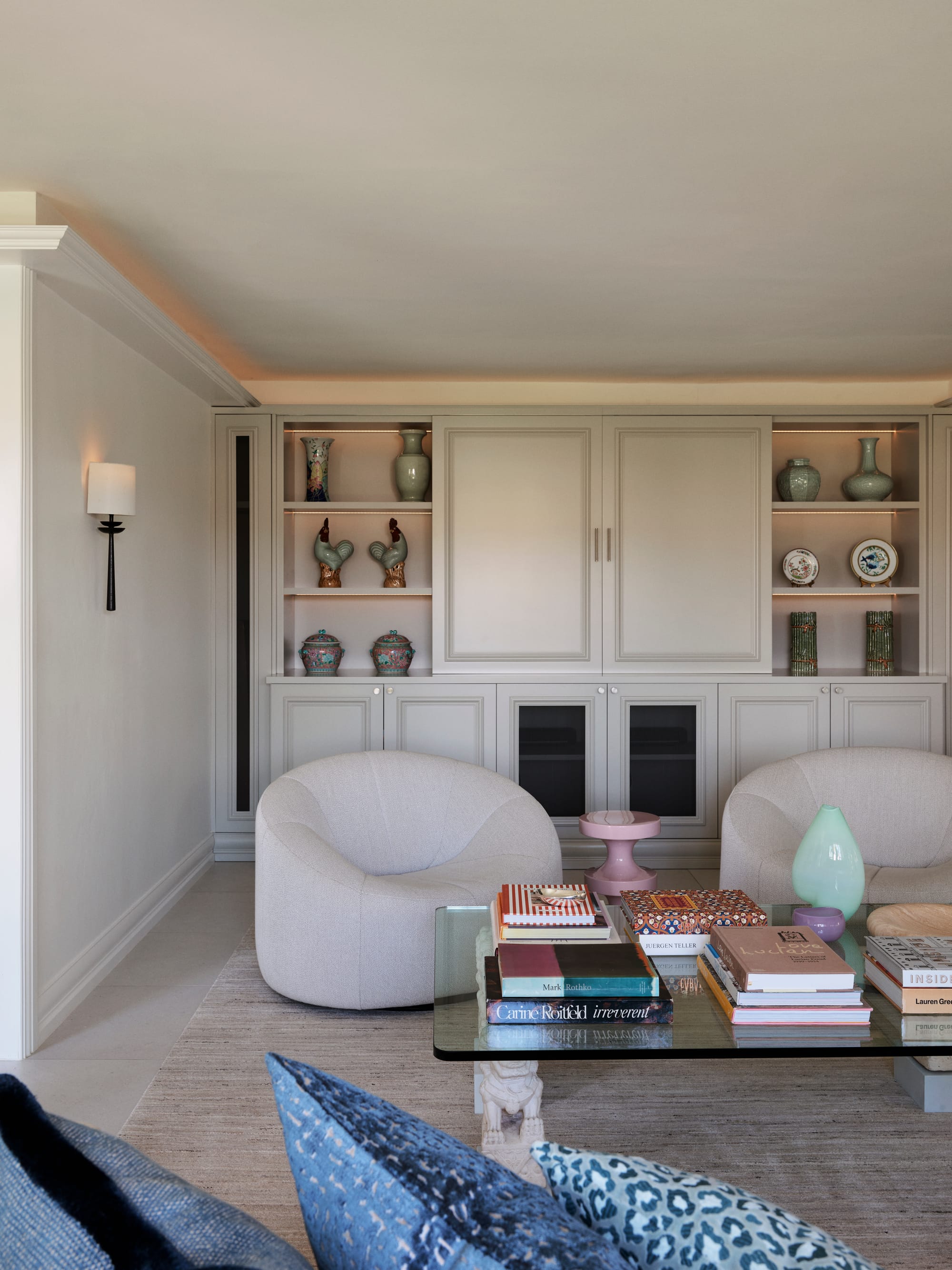 The Darling Edit by Marylou Sobel Interior Design. Photography by Anson Smart. Formal living space with two white boucle armchairs, glass coffee table, integrated cabinetry and floor rug. 