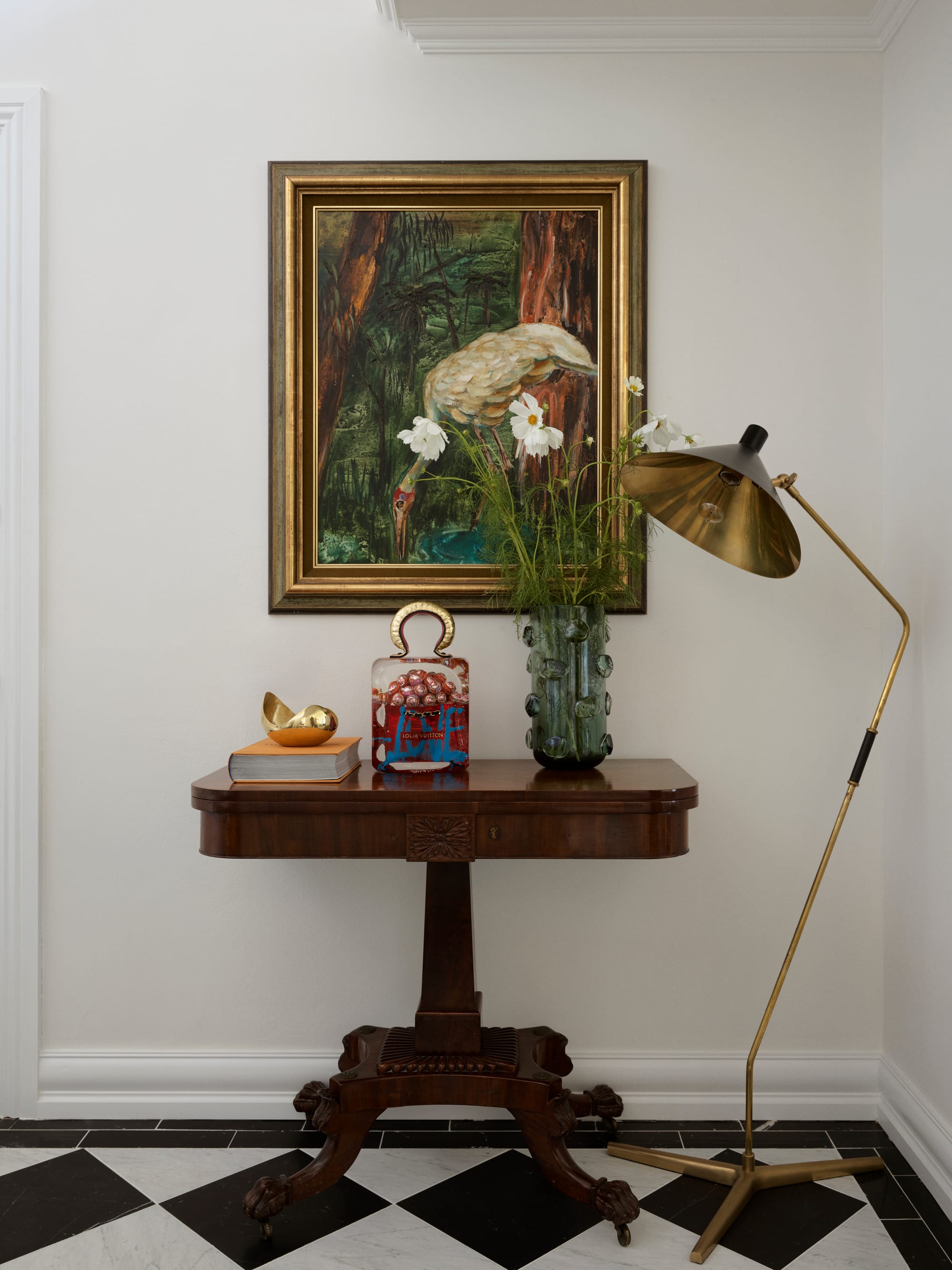 The Darling Edit by Marylou Sobel Interior Design. Photography by Anson Smart. Hall with black and white tiled checkered floors, dark timber sideboard, gold floor lamp, and wall art. 