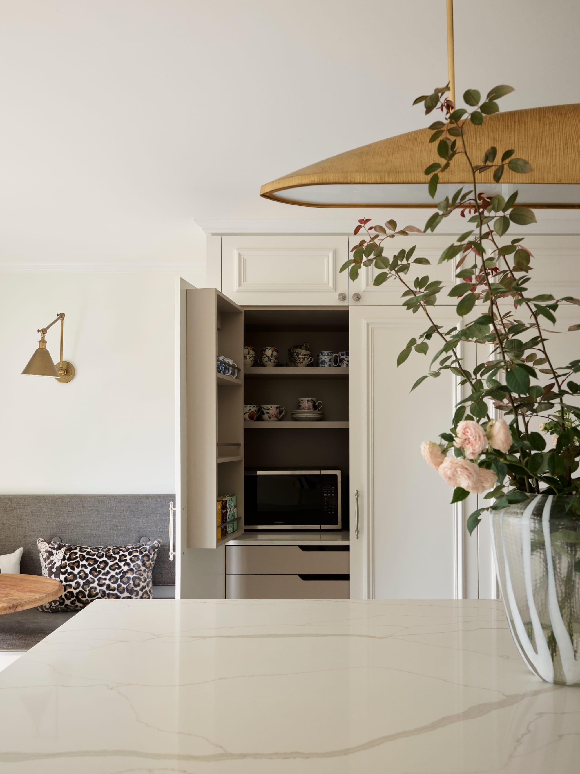 The Darling Edit by Marylou Sobel Interior Design. Photography by Anson Smart. Kitchen with stone countertop and white cabinets opened up to show internal storage. 