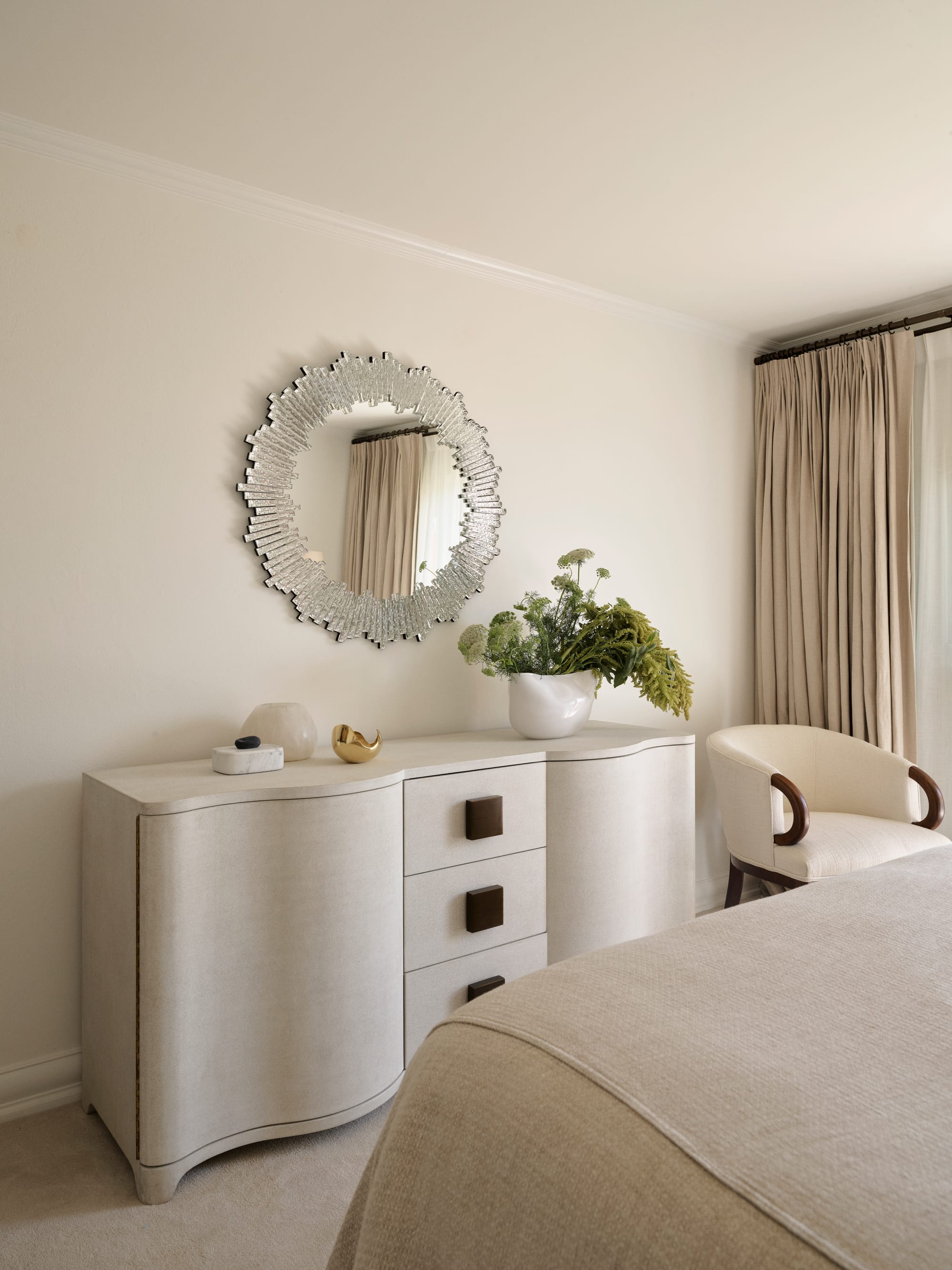 The Darling Edit by Marylou Sobel Interior Design. Photography by Anson Smart. Abstract curved beige dresser in bedroom with art deco-inspired mirror on wall. 