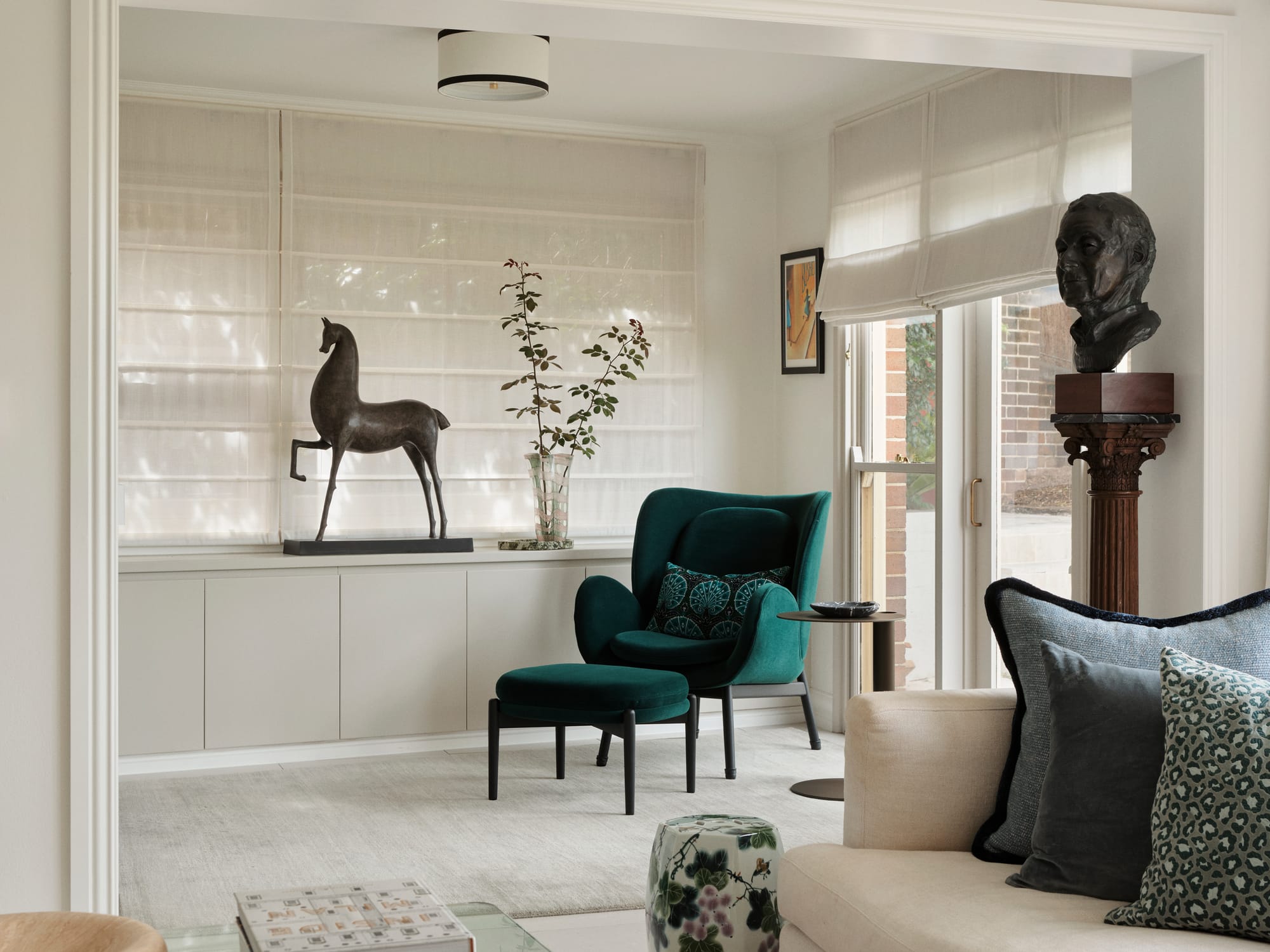 The Darling Edit by Marylou Sobel Interior Design. Photography by Anson Smart. Living space with emerald green armchair, carpeted floors, and integrated light grey cabinetry. 