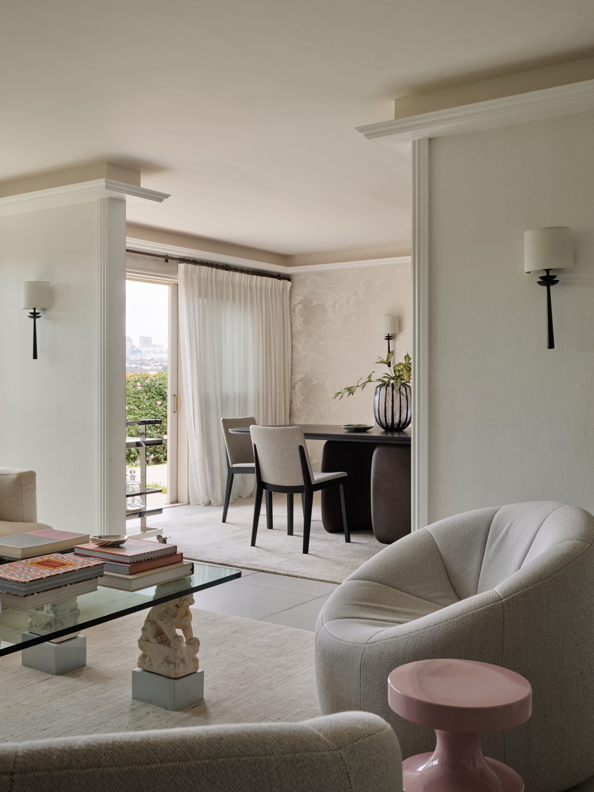 The Darling Edit by Marylou Sobel Interior Design. Photography by Anson Smart. Living space with white armchair, purple side table, and glass coffee table looking into dining space. 