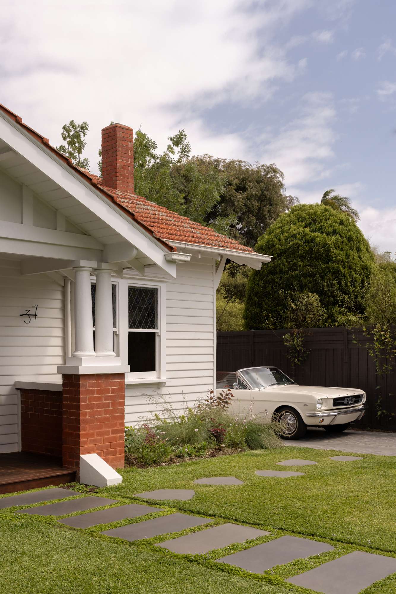 Ormond by Telha Clarke. Photography by Tim Kaye. Timber deck running alongside white brick home with timber-framed glass windows and doors. 