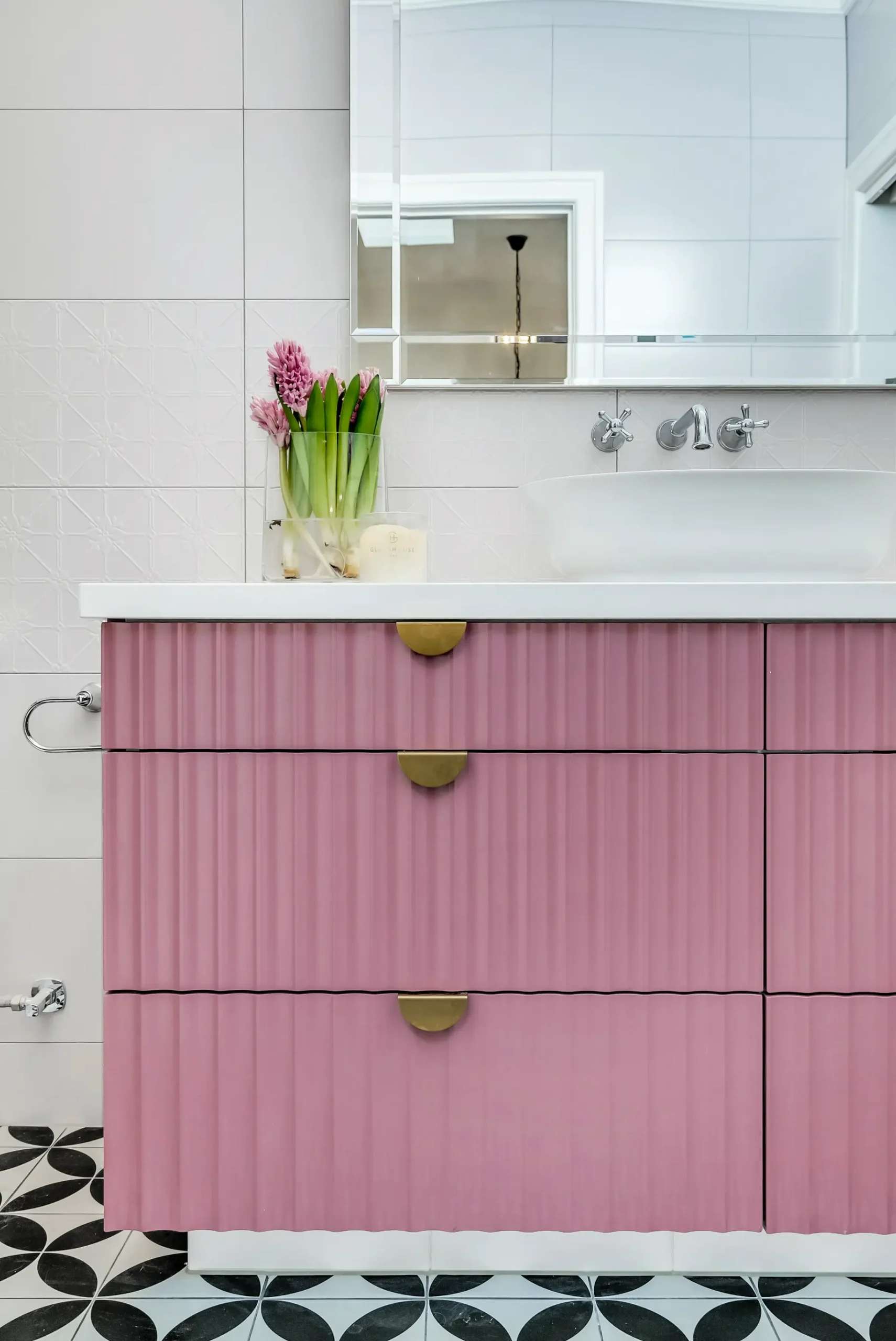 Vibrant Charm by Emotive Designs. Pink bathroom cabinetry with gold handles, patterned floor tiles and white sink. 