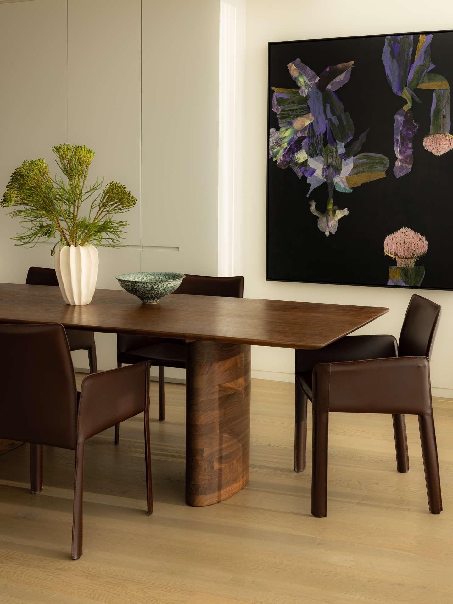 Cloud Residence by FURNISHD. Photography by Dylan James. Rich timber dining table with thick, sculptural legs, matching brown leather dining chairs, abstract wall art and light timber floors throughout. 