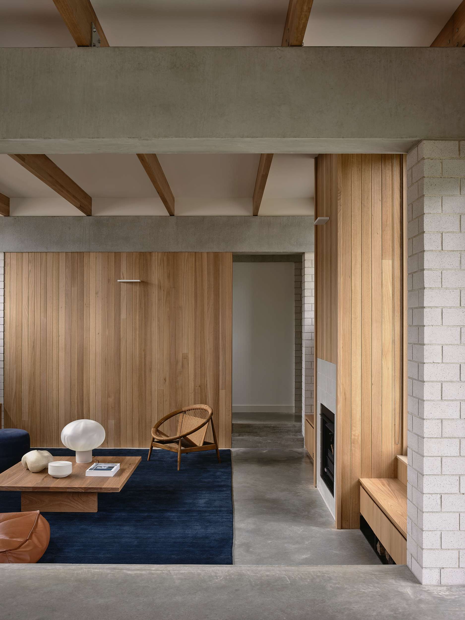 Home Pavilion by MRTN Architects. Sunken living space with concrete floors, timber clad walls and fireplace and navy rug. 