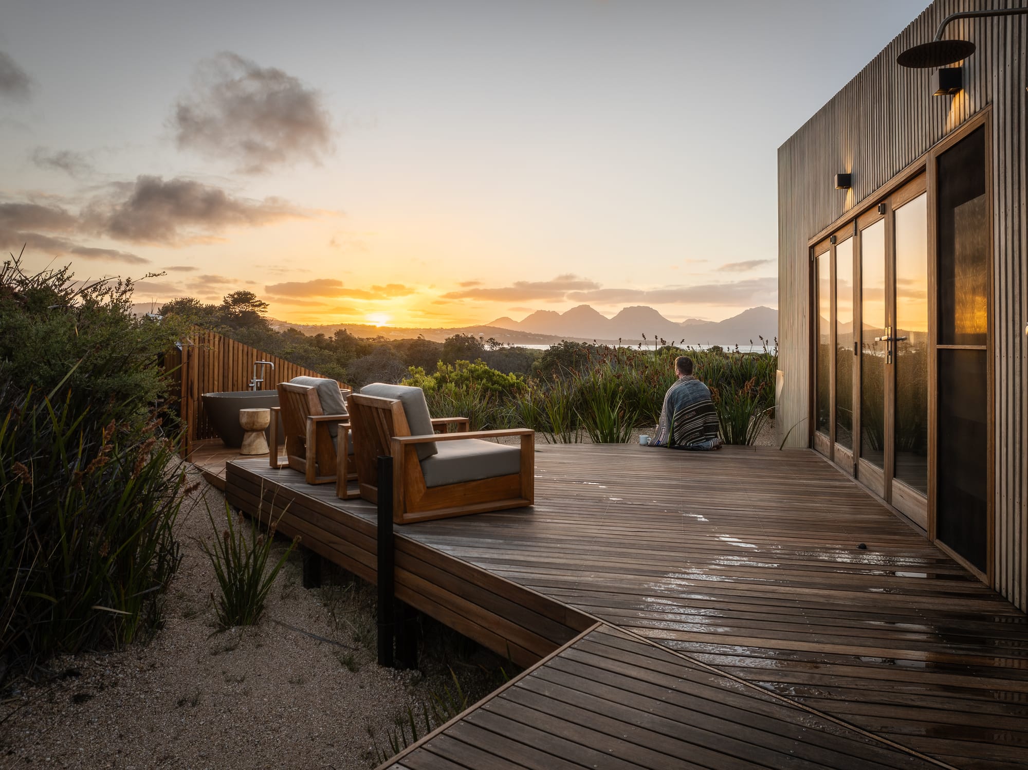 A sunset picture of Studio Tasmania with a man sitting with a blanket wrapped around him.