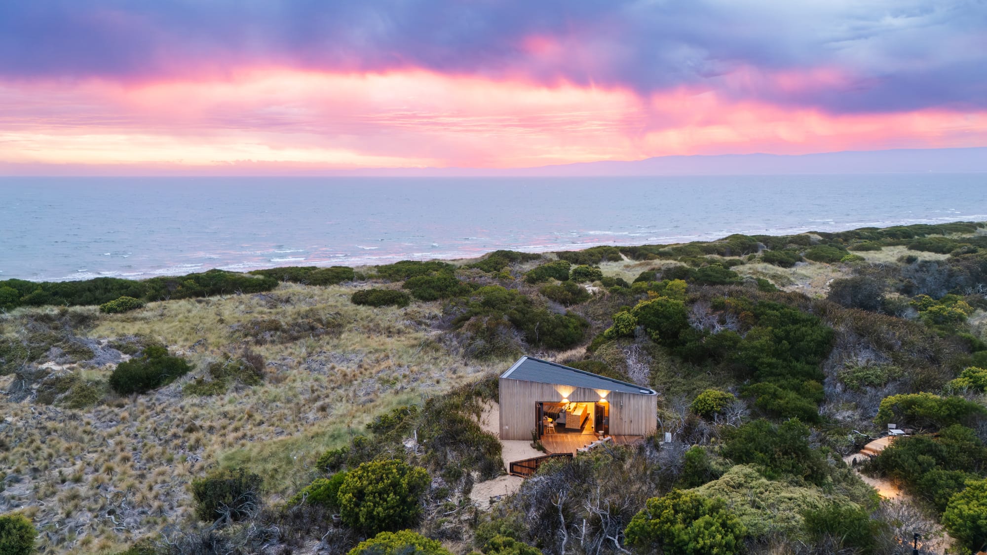 A sunset image of Studio Tasmania with a blue and pink sky over the ocean.