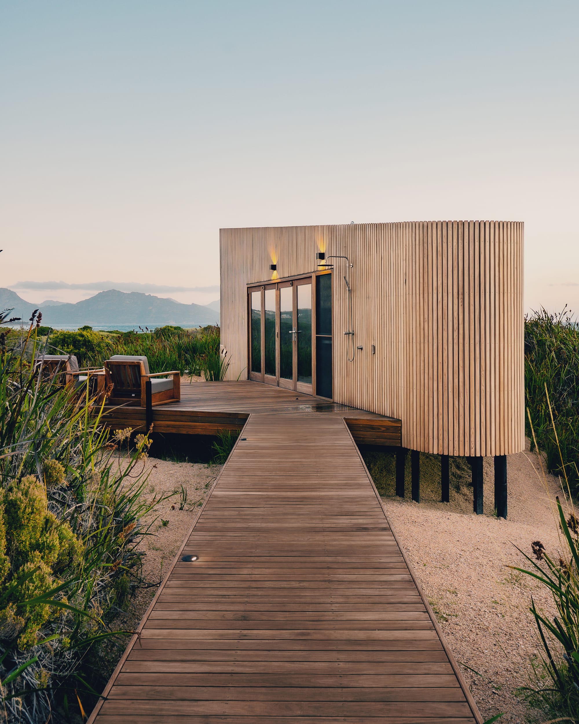 An external view of the entry of Studio Tasmania with a timber walkway and showing how the cabin sits in the landscape.