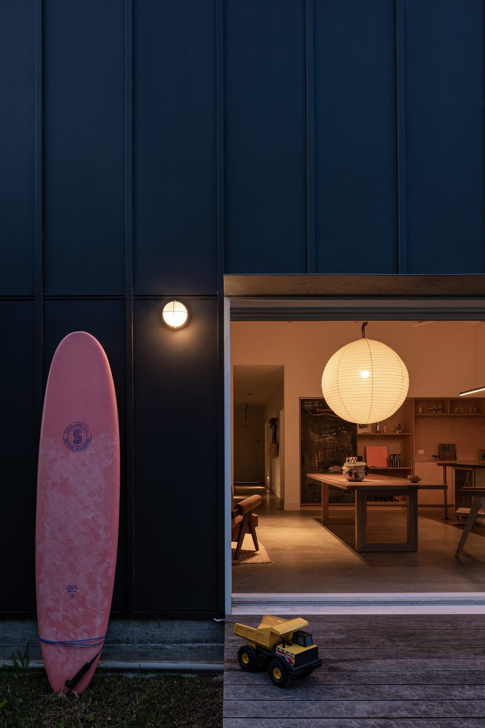 Drip-Dry House by Marker Architecture & Design. Photographed by Simon Whitbread. Grey exterior home. Back porch with wooden step. Large doorway and dinning area.