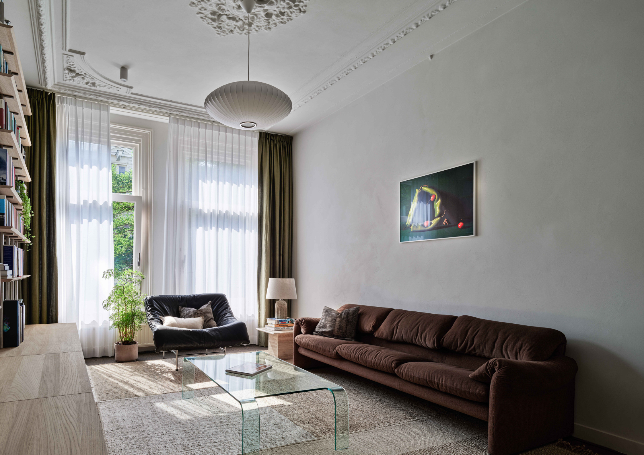 Elegant heritage-style living room with ornate ceiling details, tall sheer curtains, sculptural lighting, and contemporary furnishings.