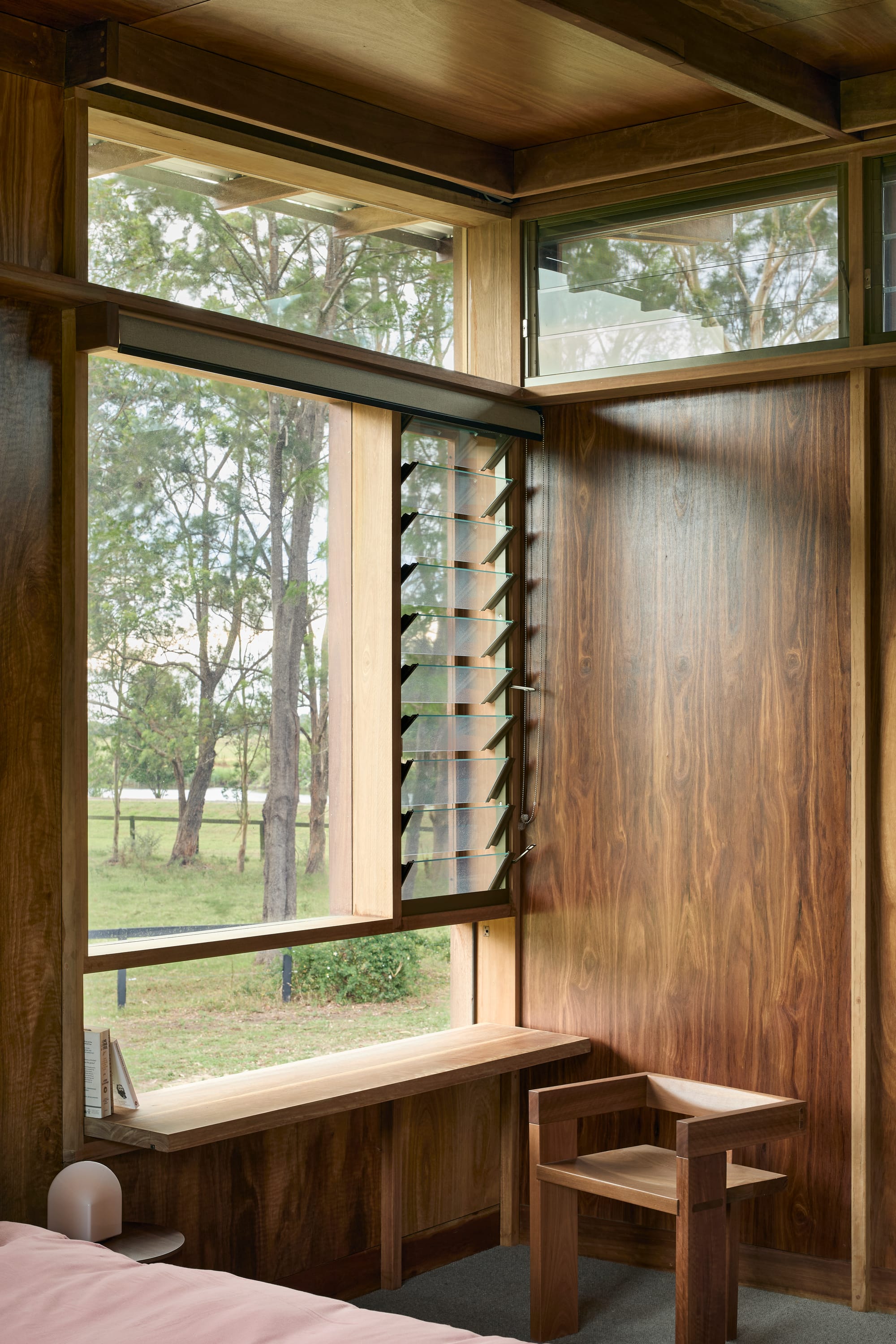 Timber-lined interior featuring custom joinery, operable louvre windows, and views to the surrounding landscape.