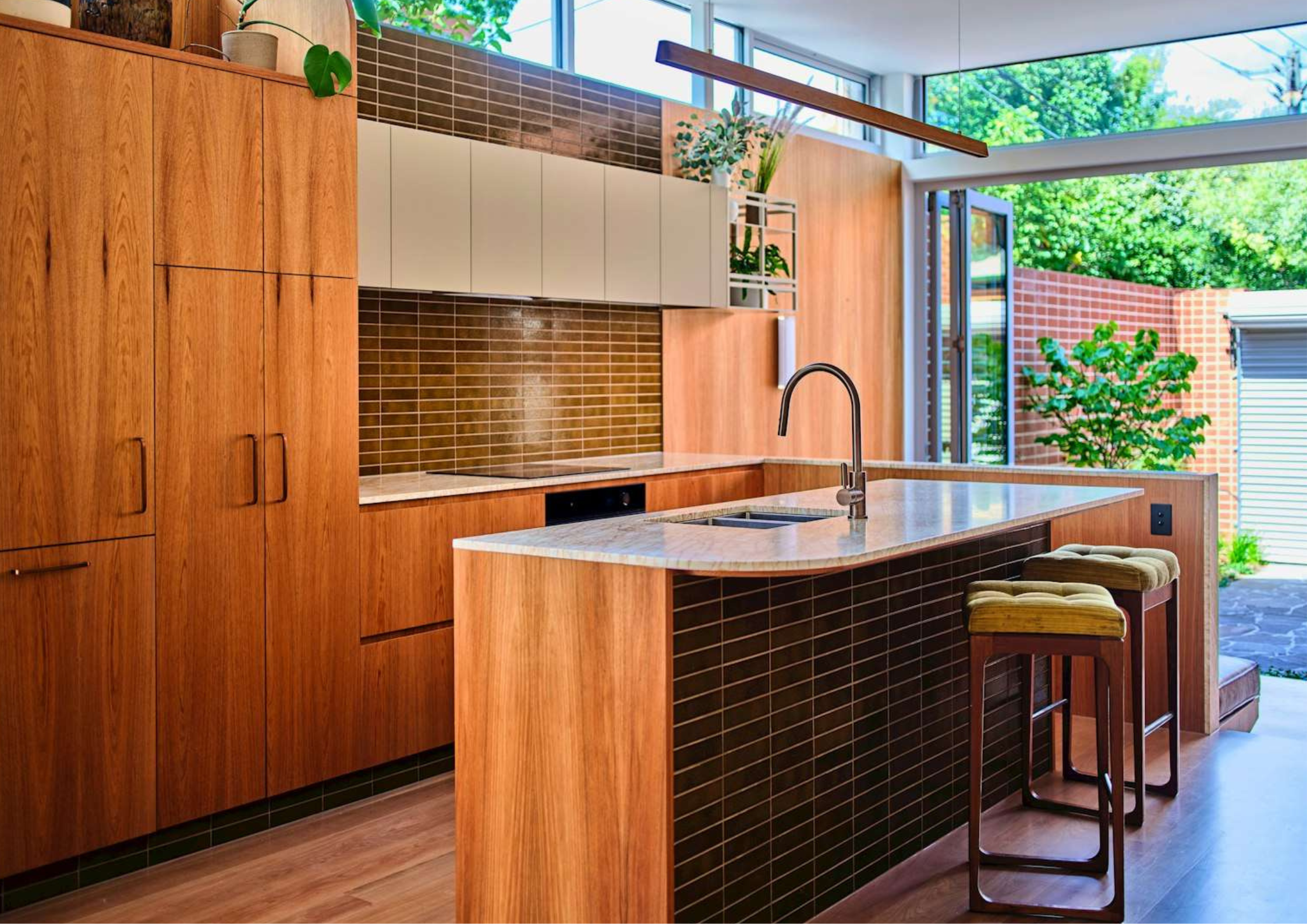 Contemporary timber kitchen with tiled island base, marble benchtops, and open connection to outdoor courtyard.