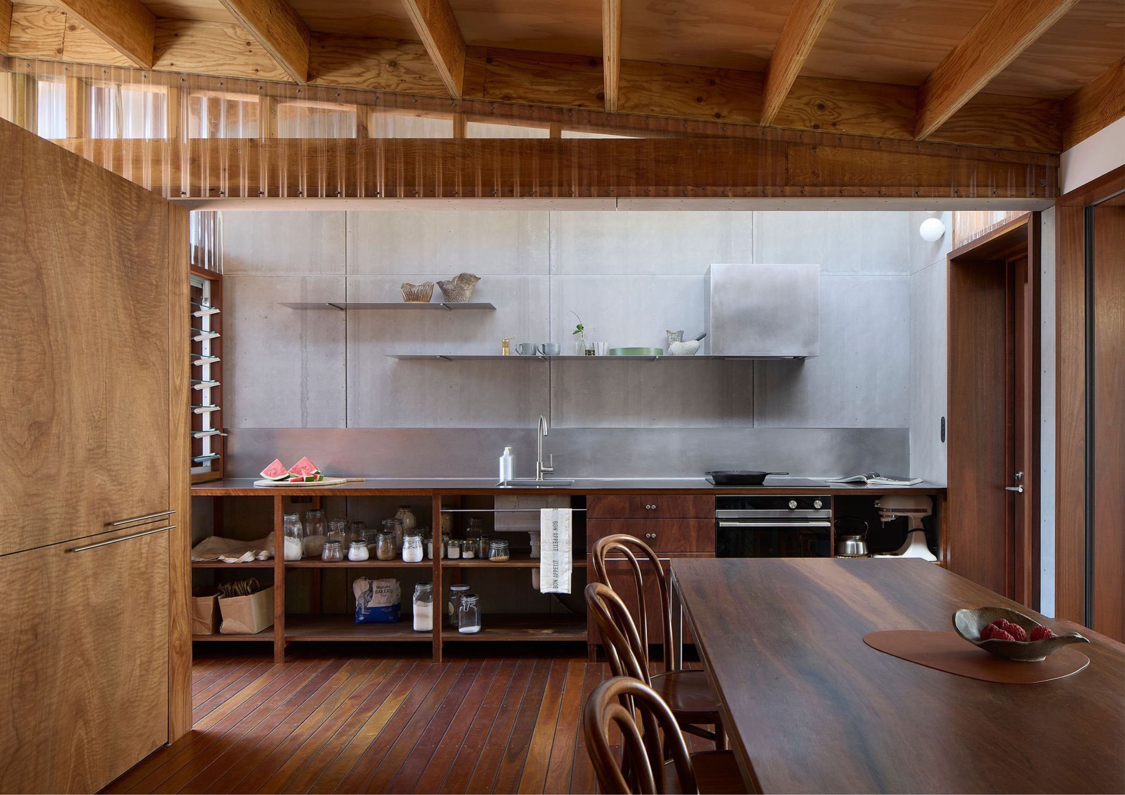 Rustic timber kitchen with exposed beams, stainless steel splashback, and handcrafted detailing.