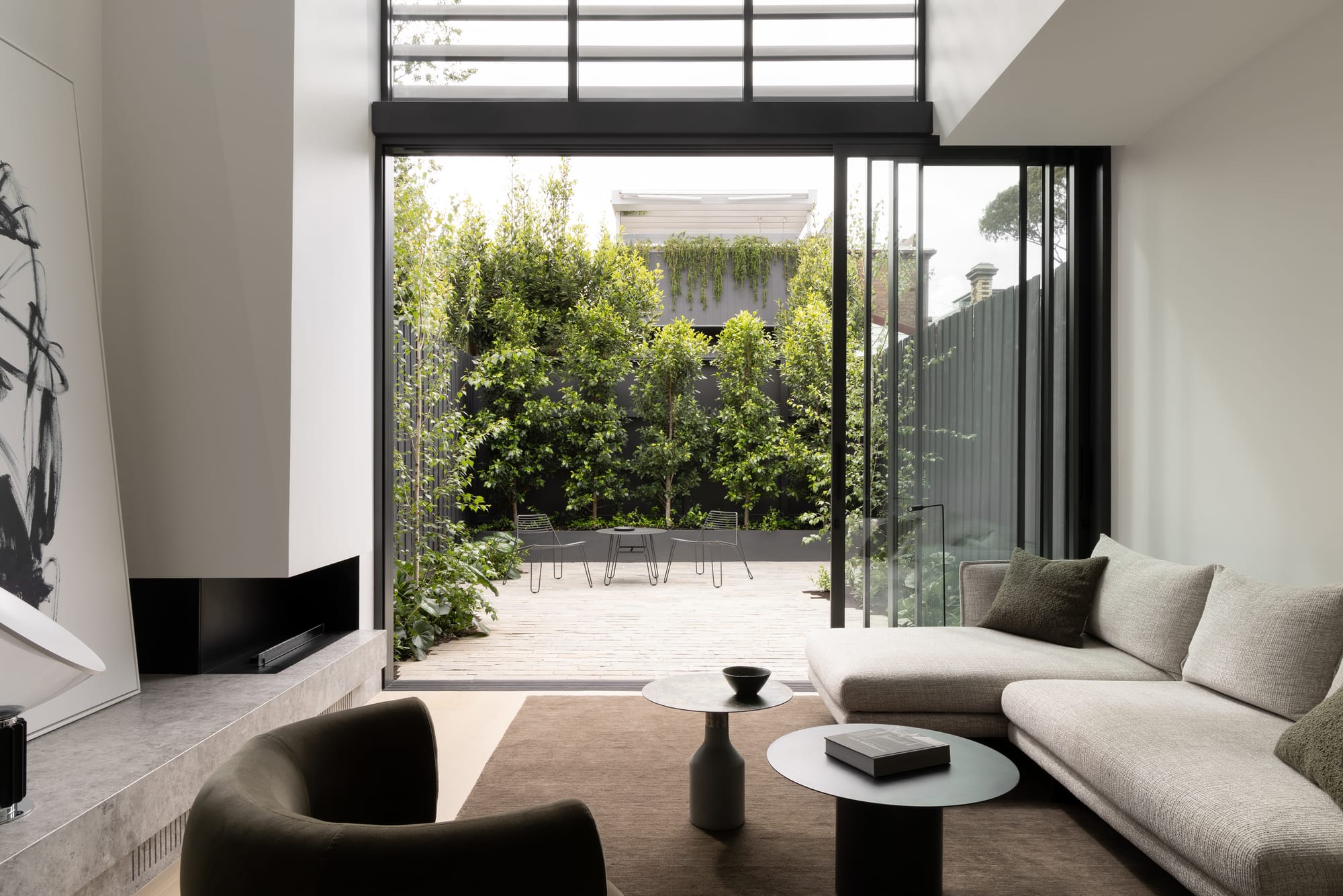 Modern façade with black horizontal louvres above a glass entry and minimalist landscaping.