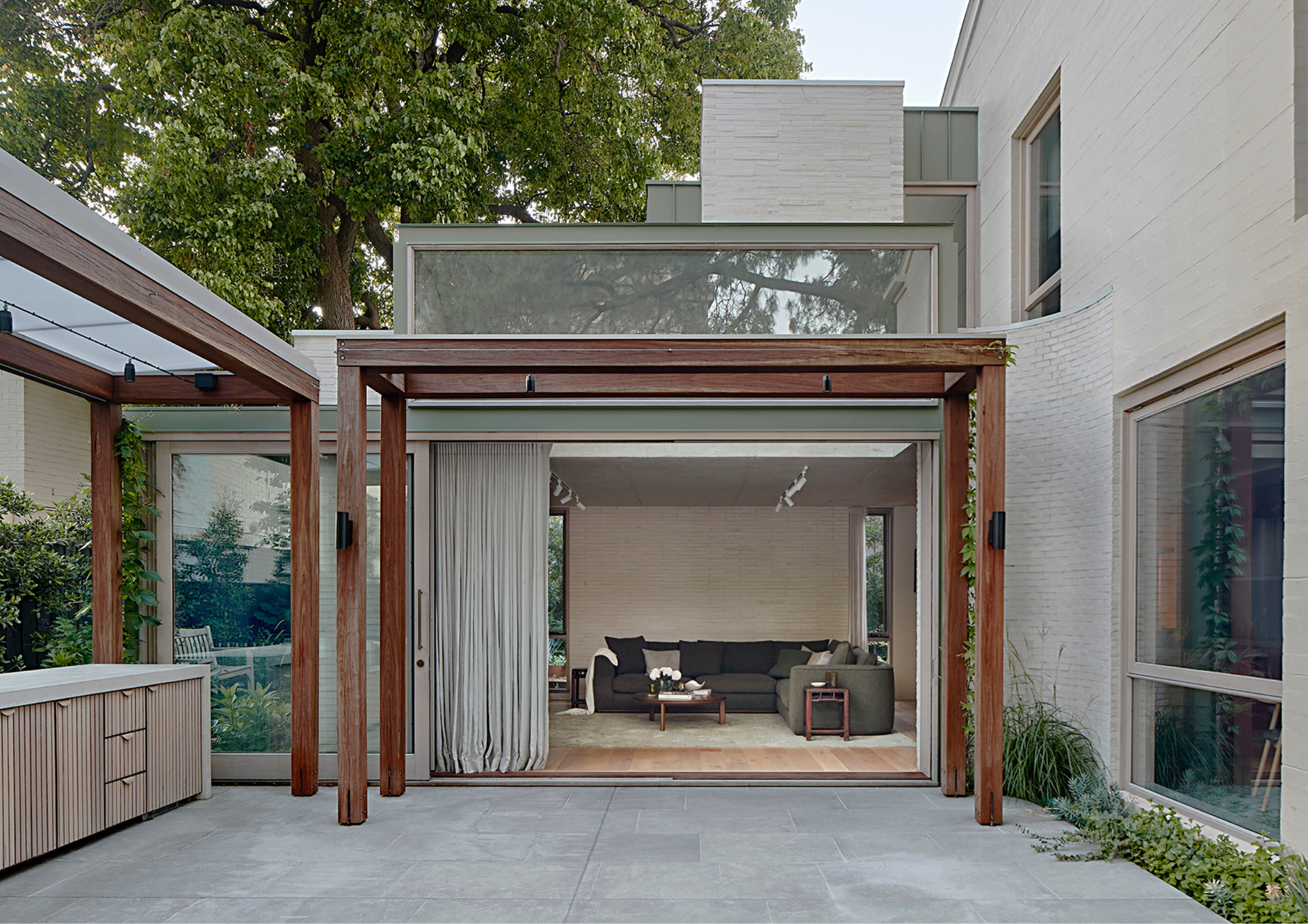 Village Studio by mcmahon and nerlich. Photography by Dave Kulesza. Marble fireplace, grey and green couch and armchairs. Floating timber shelves.