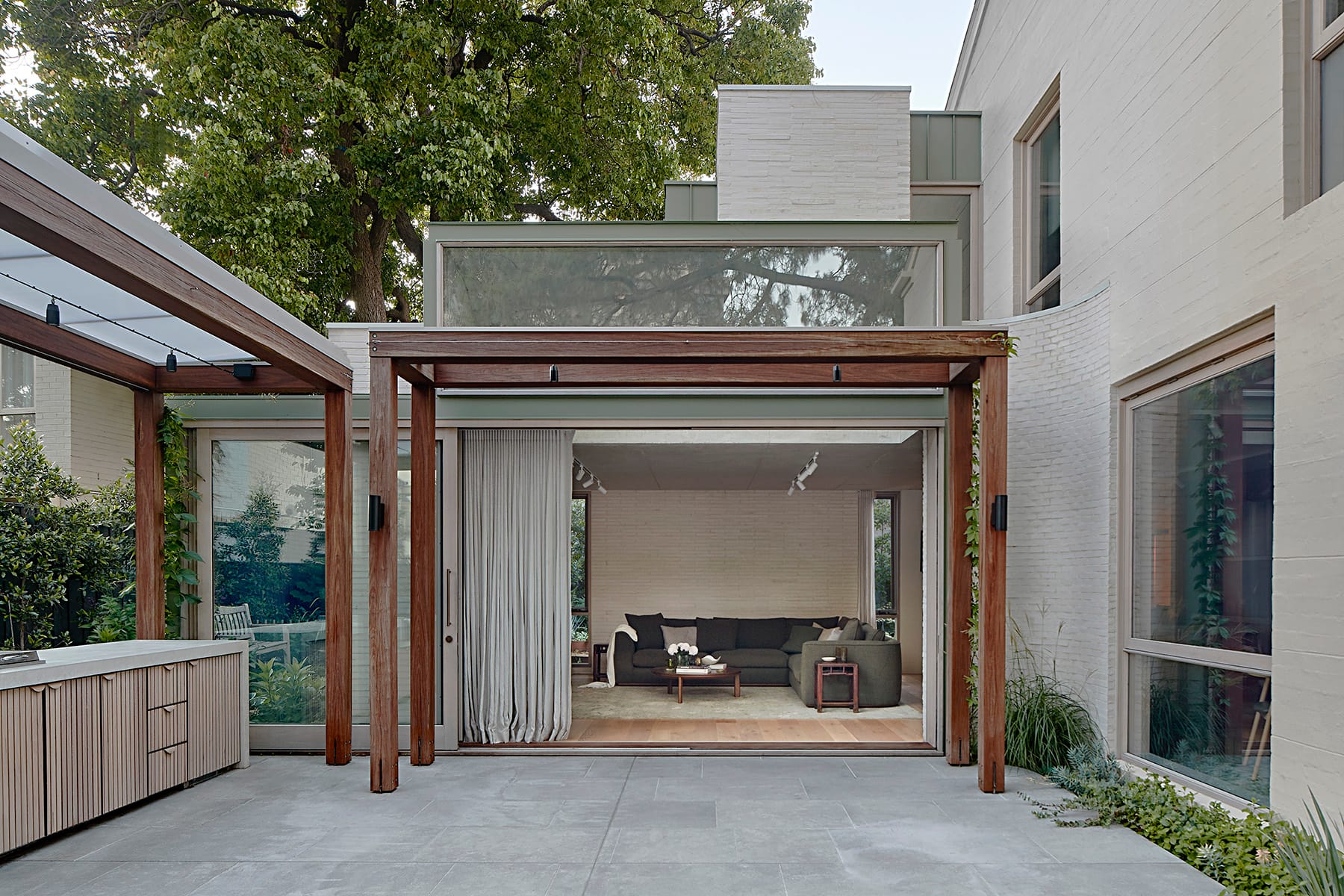 Village Studio by mcmahon and nerlich. Photography by Dave Kulesza. Marble fireplace, grey and green couch and armchairs. Floating timber shelves.