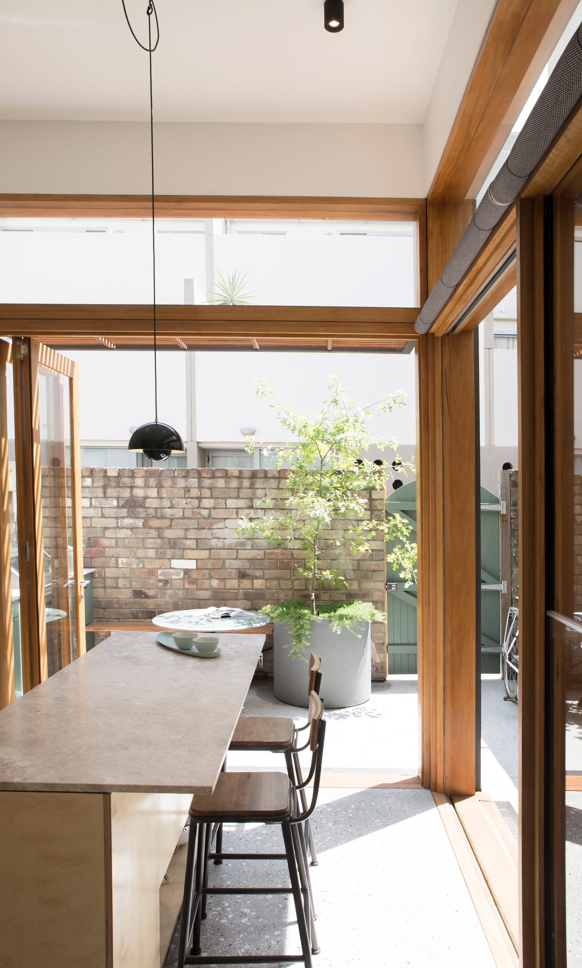 Light-filled kitchen and dining space featuring timber joinery, large glazed openings, and indoor-outdoor connection.