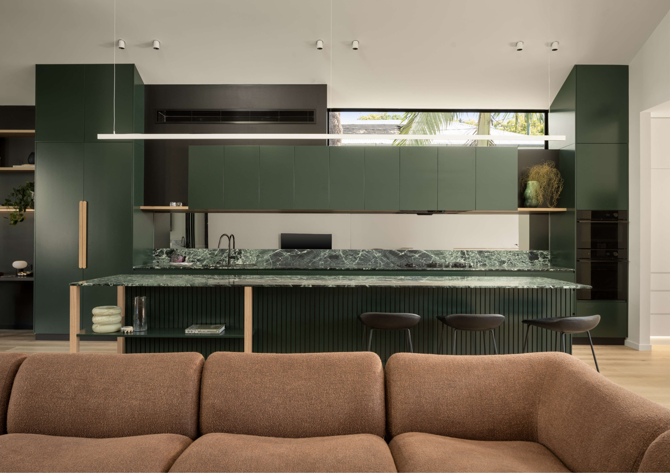 Contemporary green kitchen with fluted detailing, stone benchtops, and integrated open-plan living.