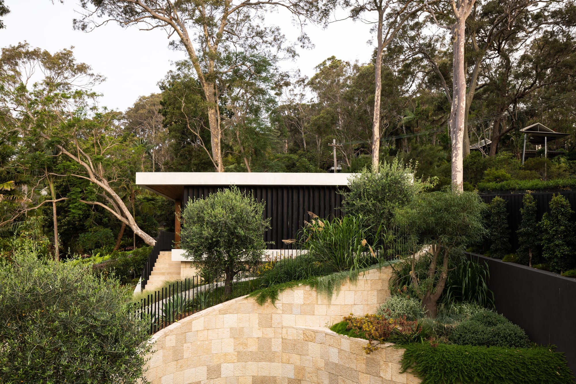 Contemporary home by Marker Architecture nestled into a landscaped hillside surrounded by mature trees and native gardens.