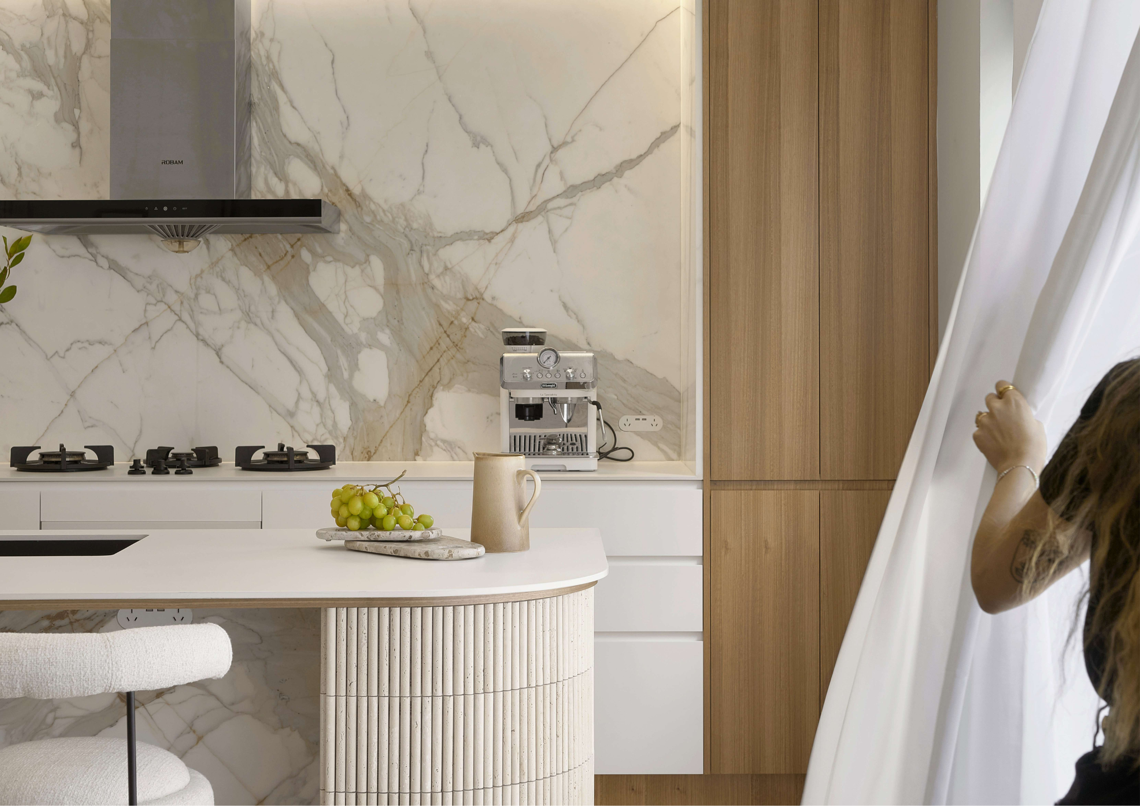 Luxury marble kitchen with fluted island detailing, integrated appliances, and warm timber joinery.