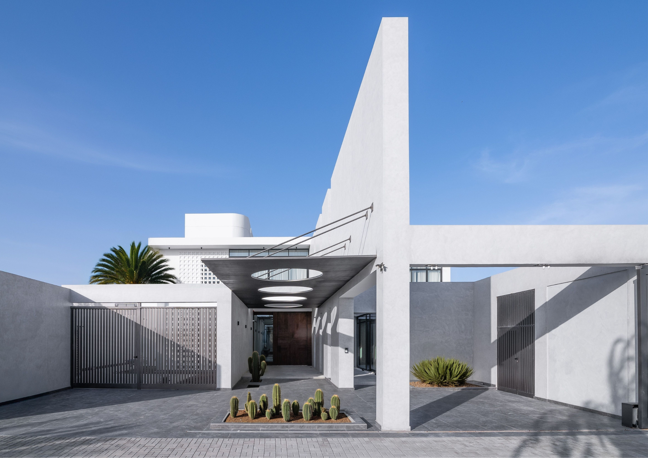 Minimal white modern house with geometric forms, circular skylights, and courtyard planting.