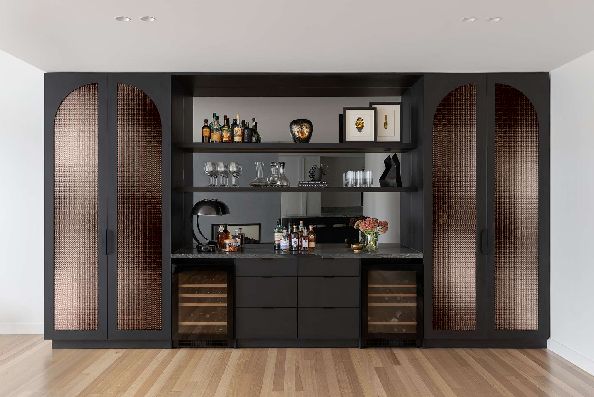 Custom built-in bar joinery with arched cane-front cabinet doors, marble benchtop, open shelving and dual wine fridges in the Caulfield Project by SMD Projects.