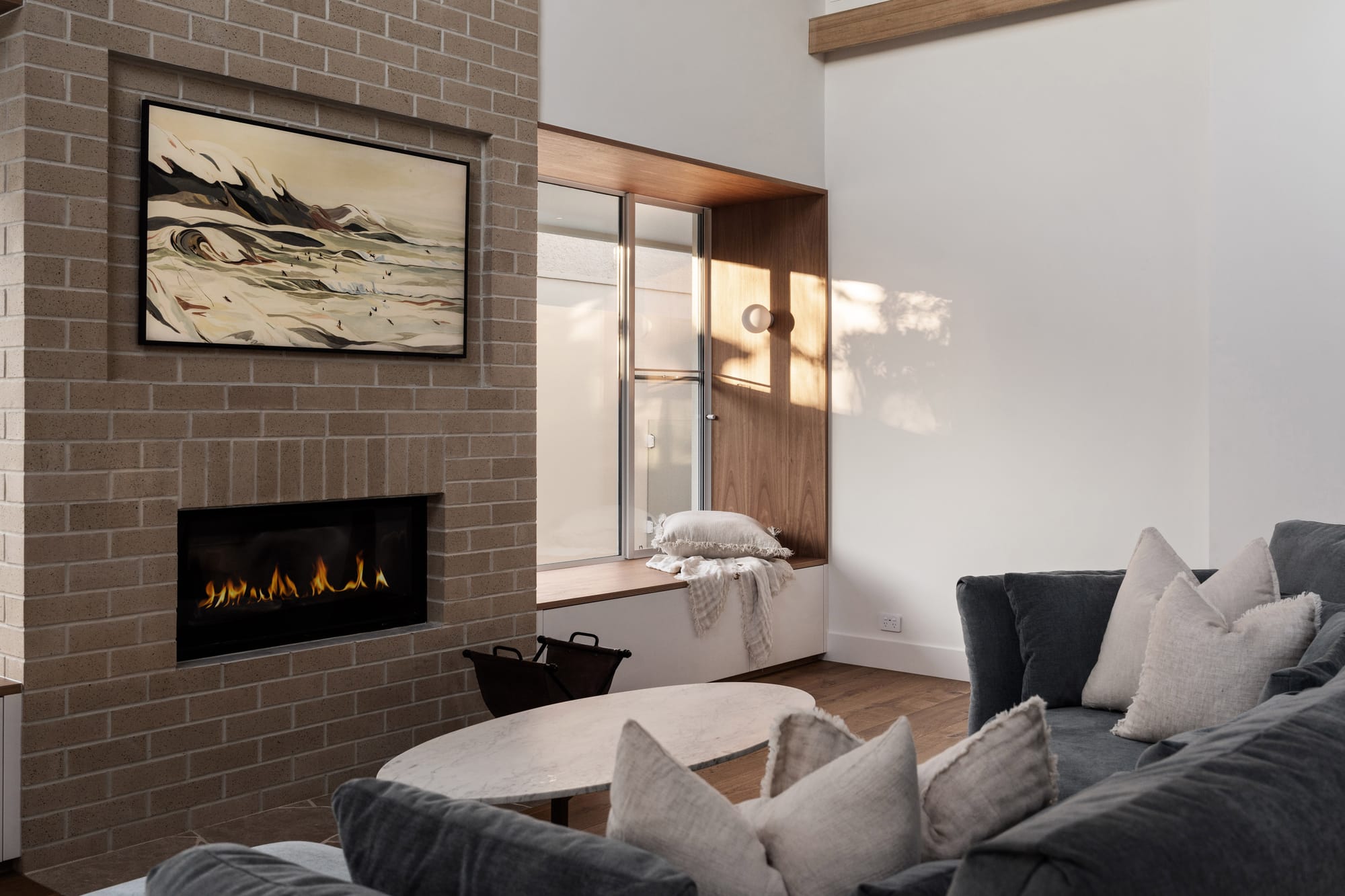 Living room in Playhouse by Trennel Architecture featuring a brick fireplace, timber-lined window seat, high ceilings and soft natural light filtering through glazing.