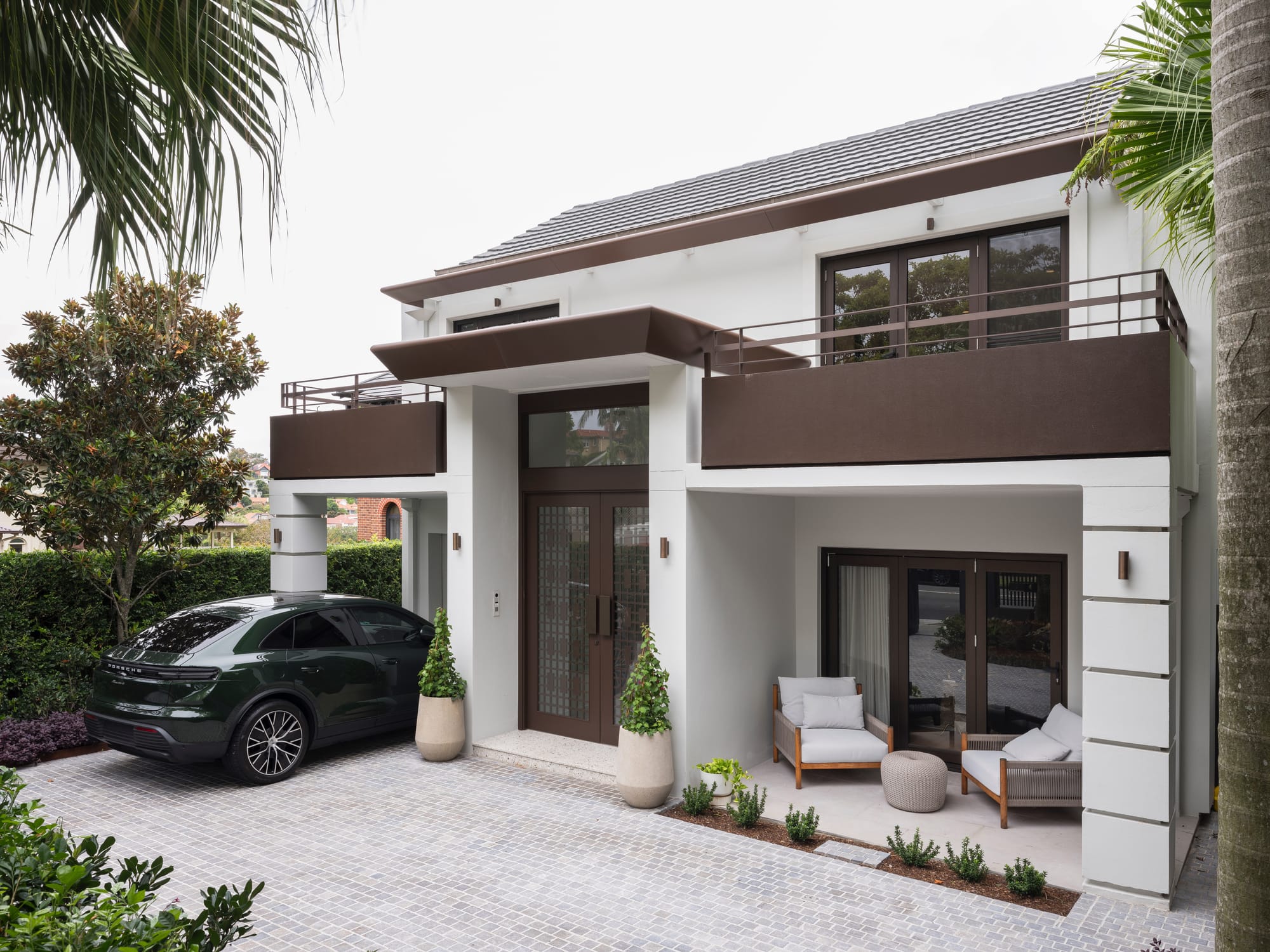 Exterior facade of Queen Street Mosman residence with dark canopy, cobblestone driveway and outdoor seating, McNally Architects